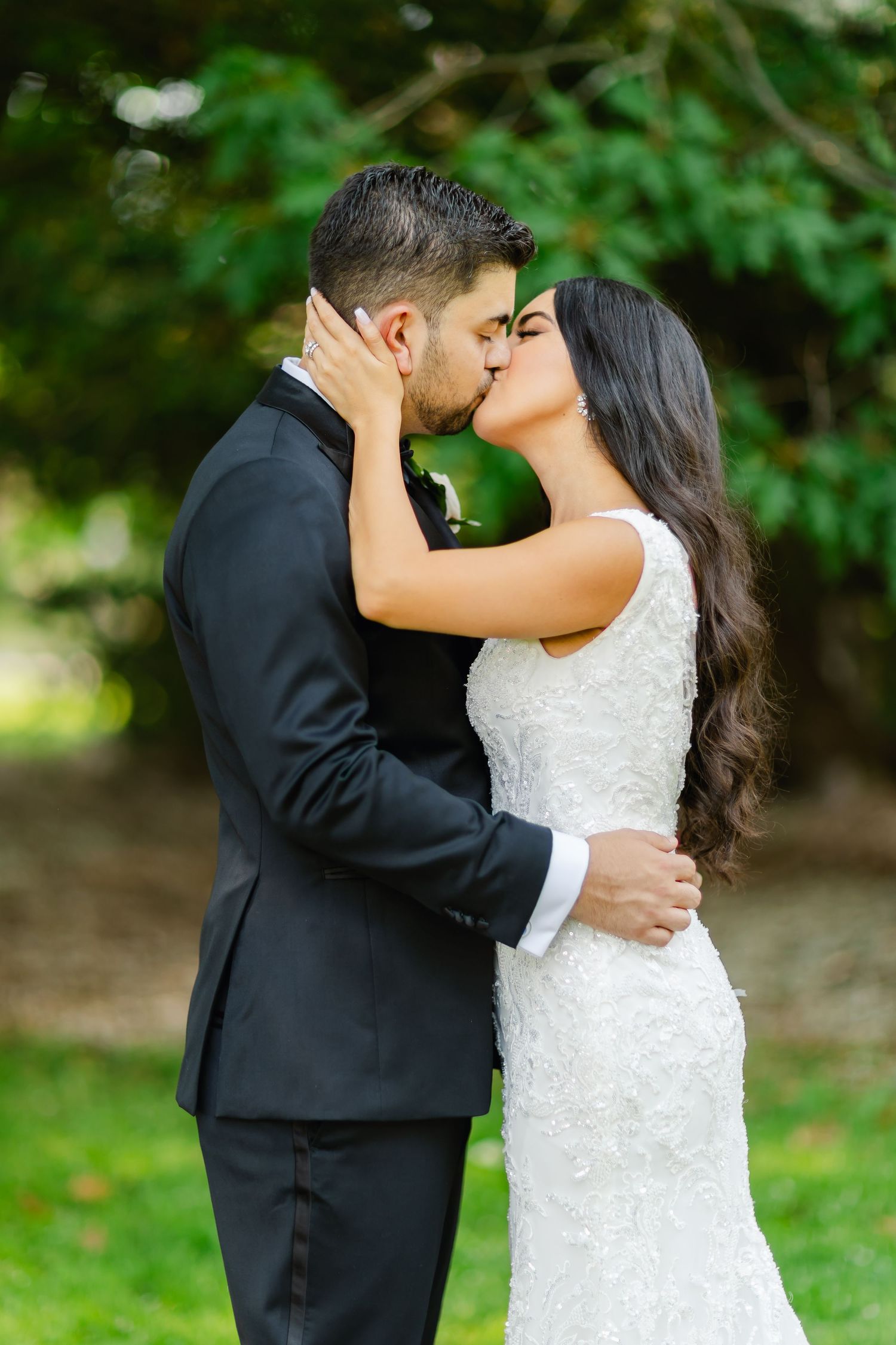 A tender wedding moment captured as the couple shares a kiss in a garden setting.
