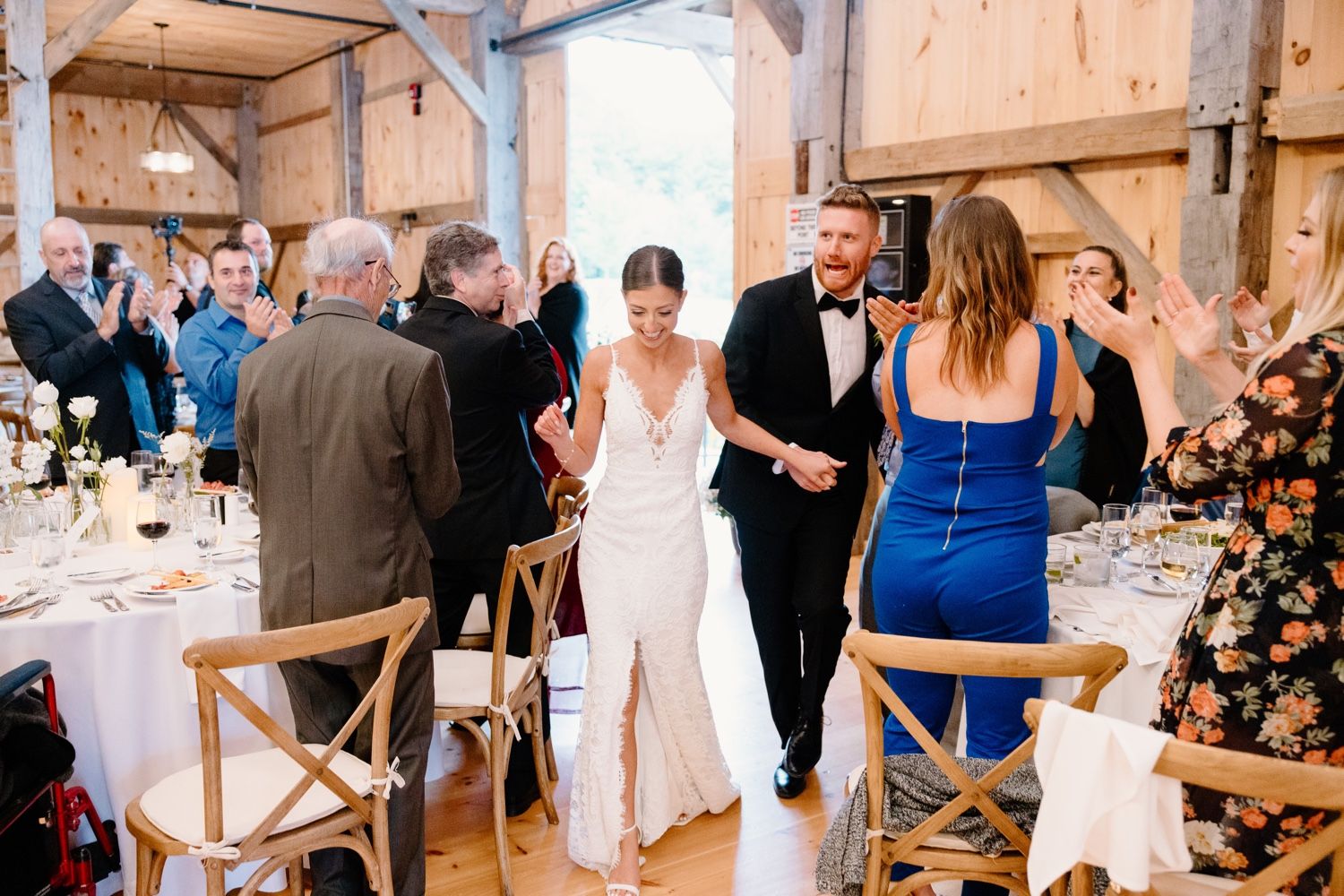 Wedding reception celebration in rustic barn venue with guests at decorated tables.