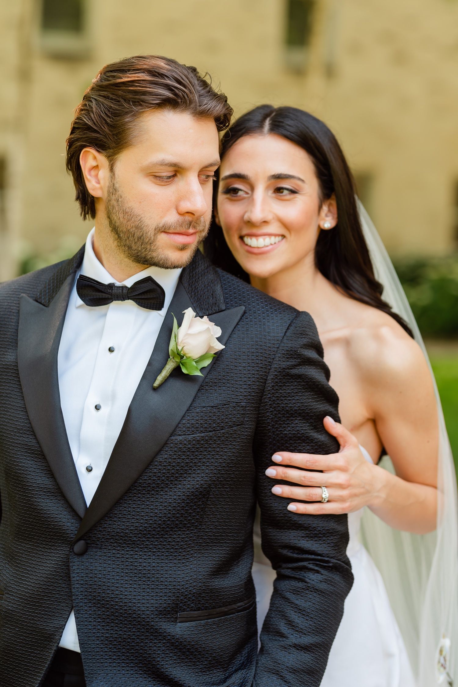 A romantic wedding portrait of a couple in formal attire with the groom in a black tuxedo and bride in white dress.