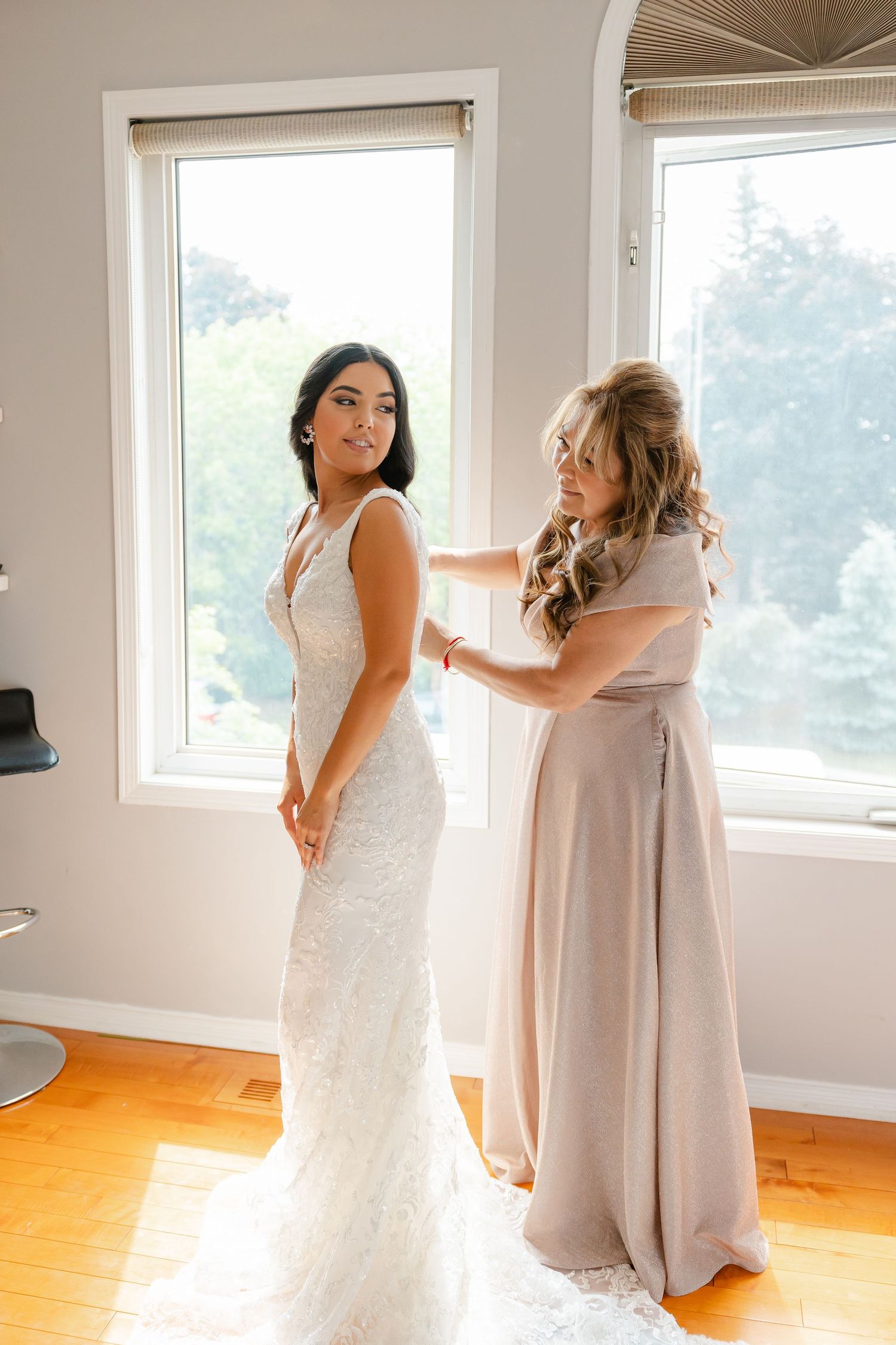 A beautiful wedding dress fitting moment captured in natural light by large windows.