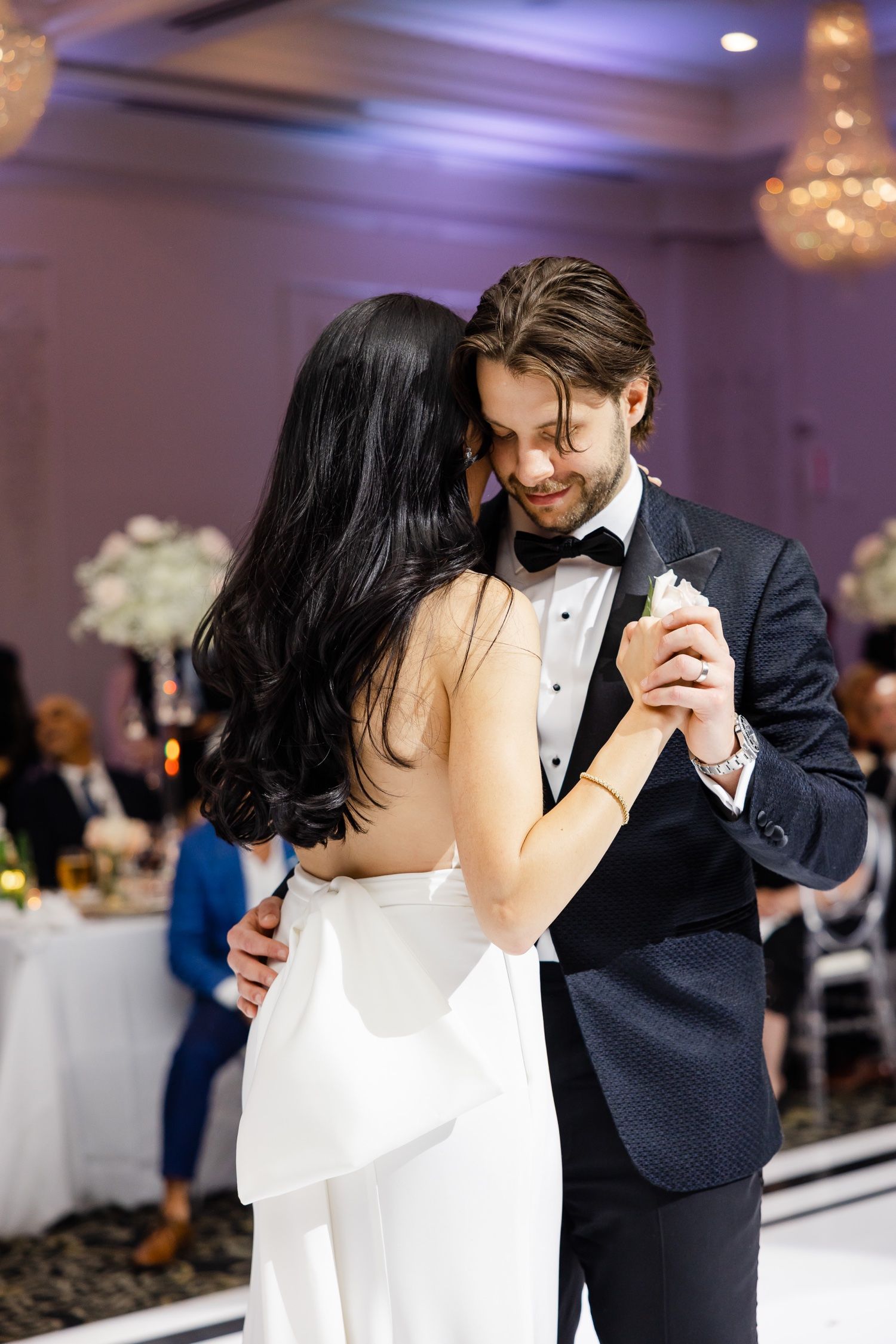 Intimate moment shared during first dance at elegant purple-lit reception venue.