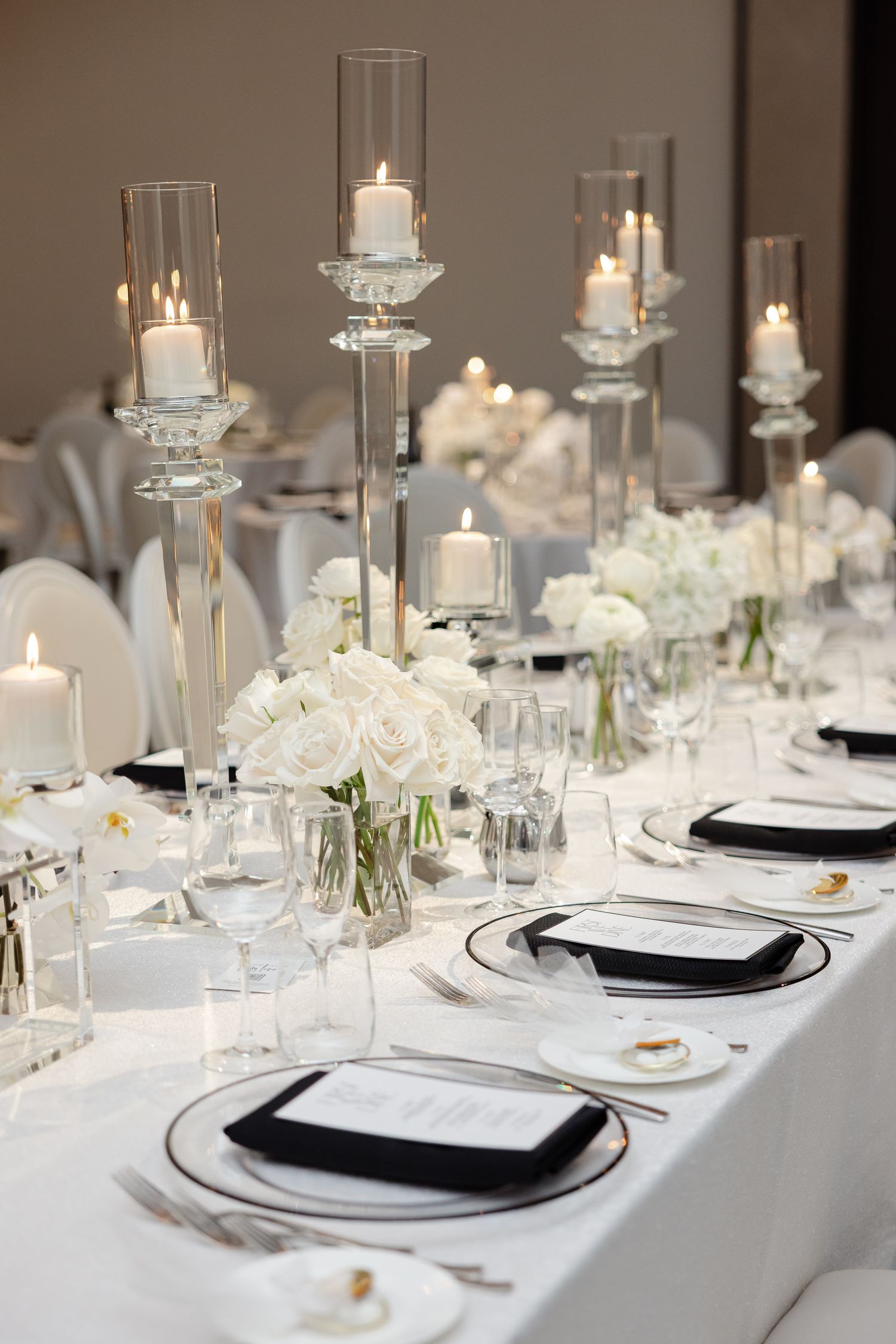 Elegant white and silver table settings with crystal candleholders and delicate floral centerpieces create a luxurious reception.