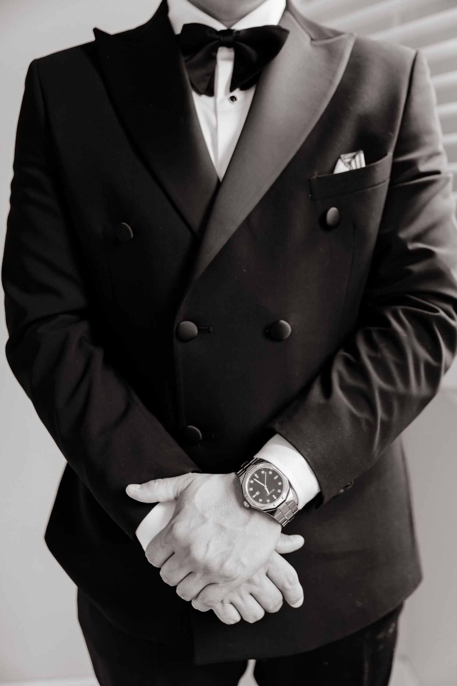 Professional black and white photo of groomsmen in tuxedos showing elegant formal wear details.
