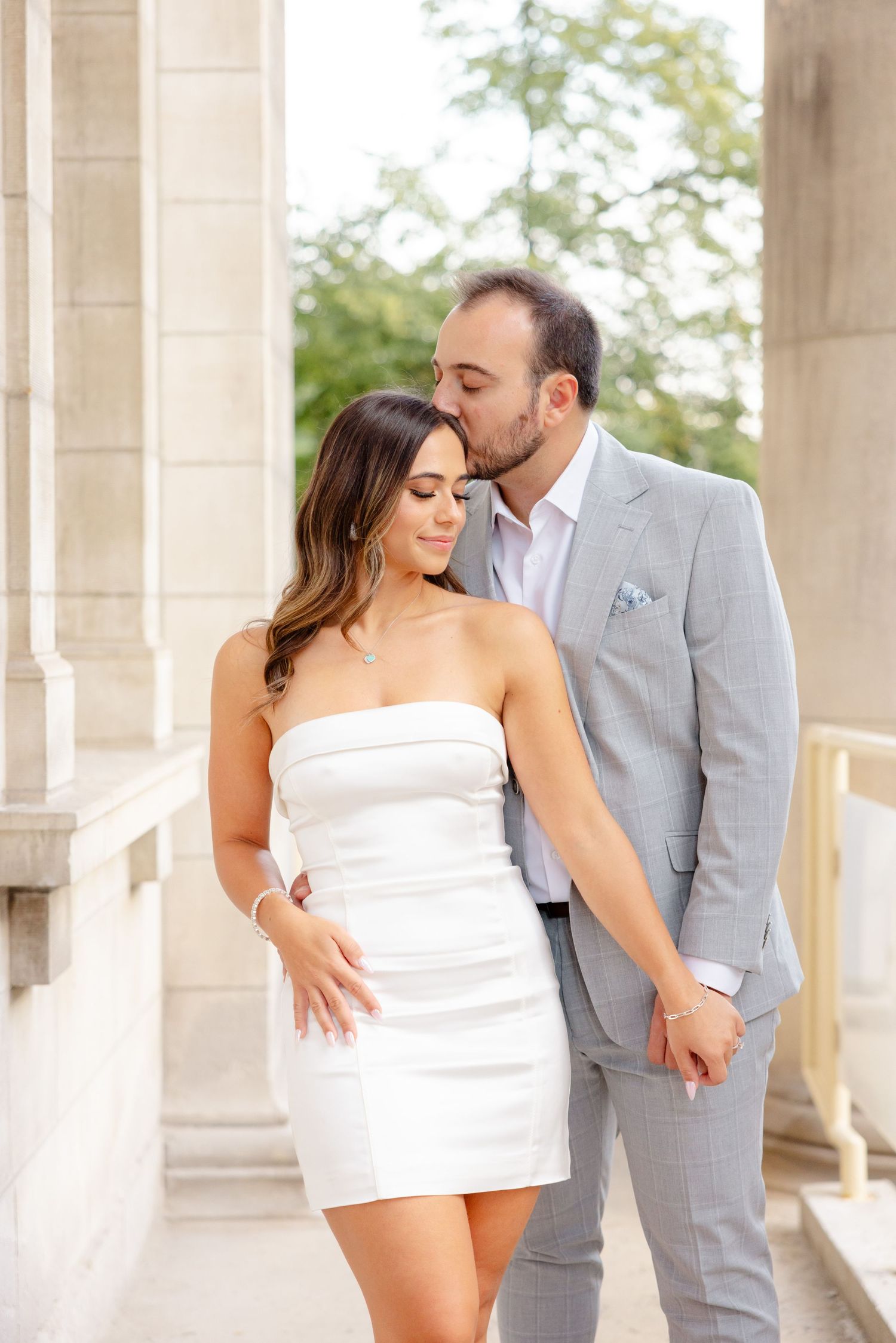 Intimate portrait of a couple sharing a tender moment between stone columns.