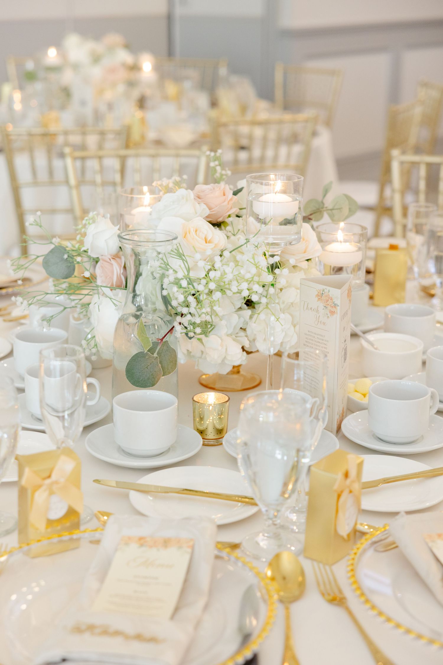 Elegant table setting with white hydrangea centerpiece, gold accents, and tea cups.