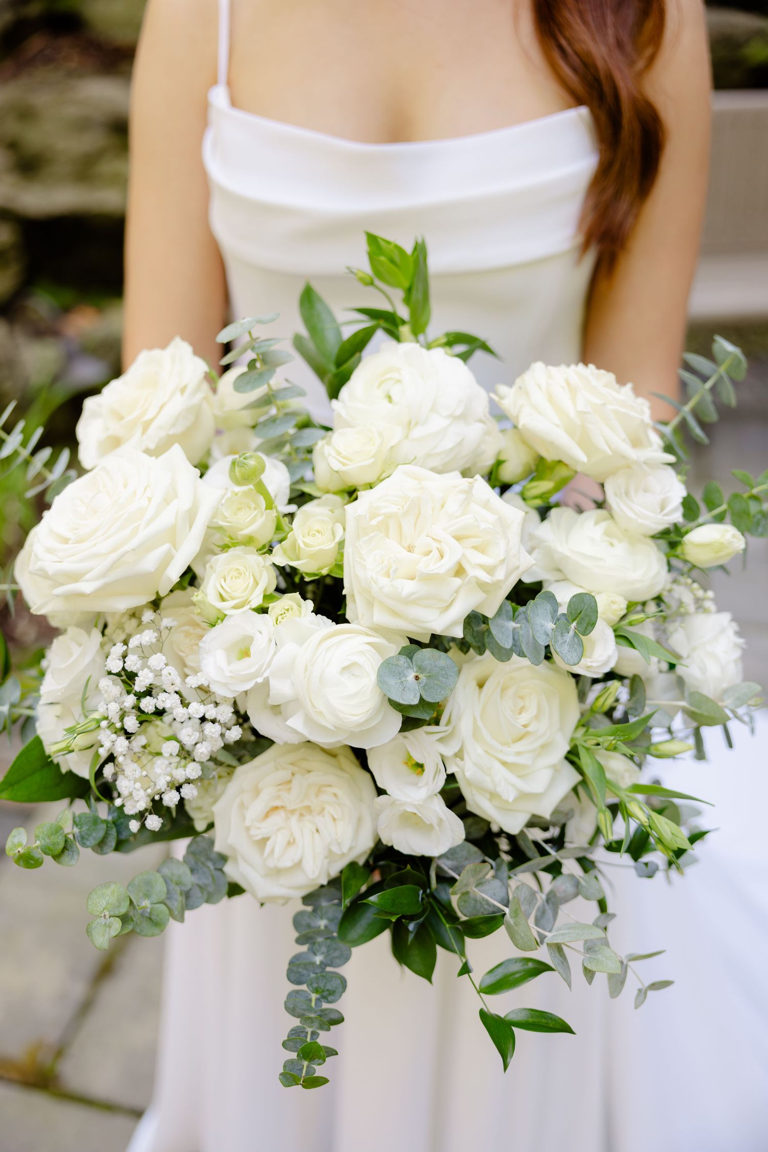 Close-up of an elegant white and green bridal bouquet with roses and eucalyptus.