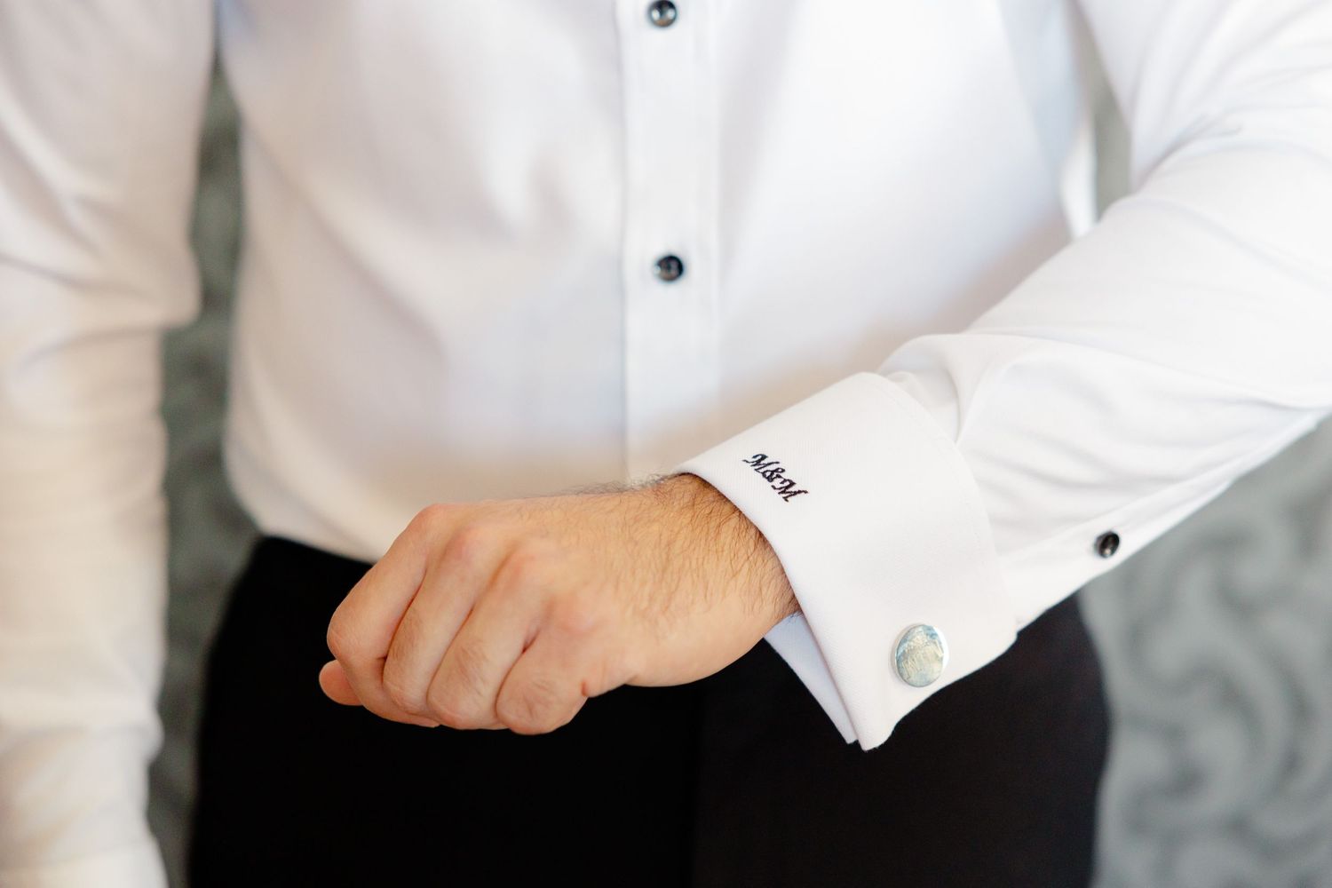 Close-up of a formal white dress shirt cuff with black buttons.