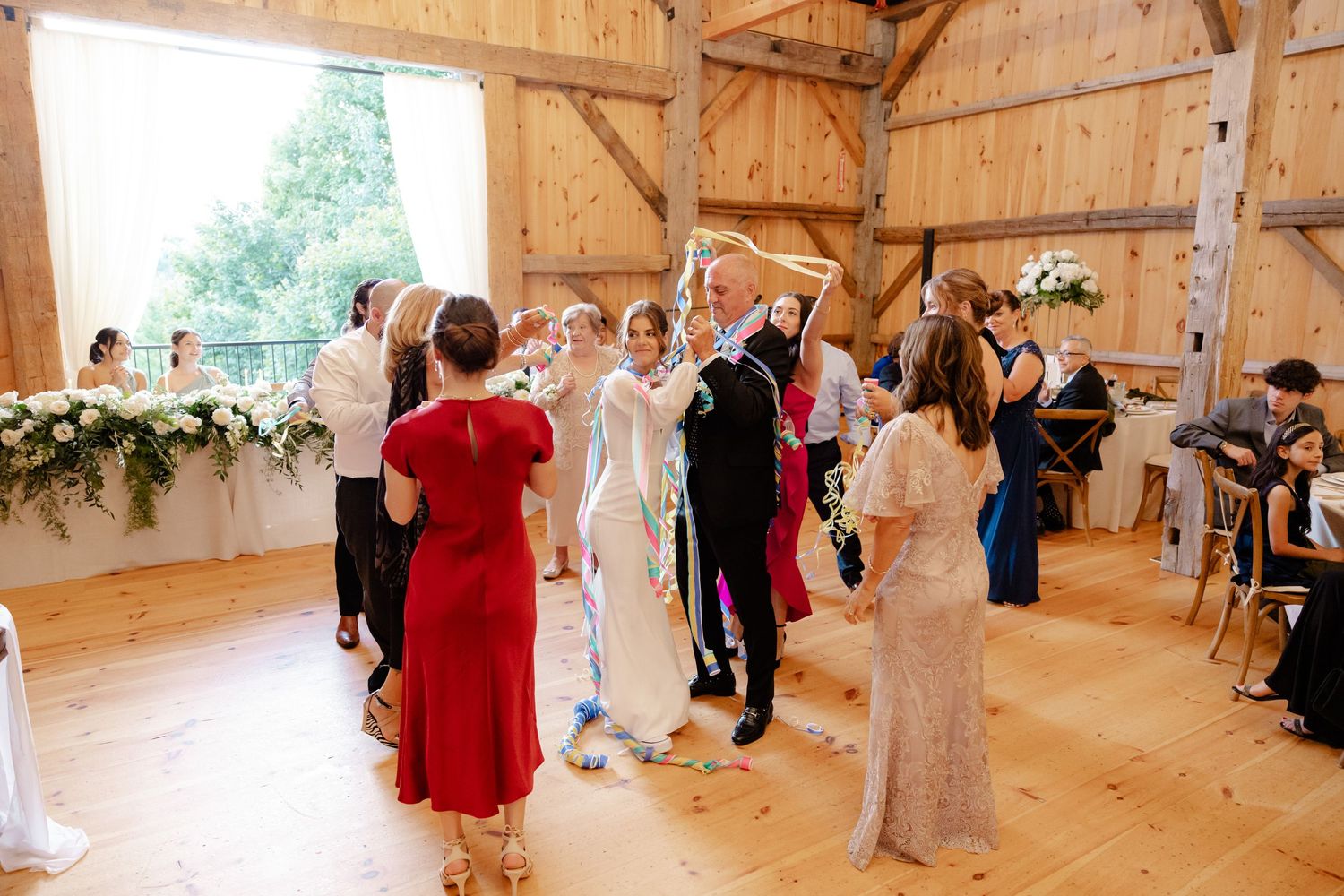 Wedding guests dancing and celebrating in a rustic barn venue.