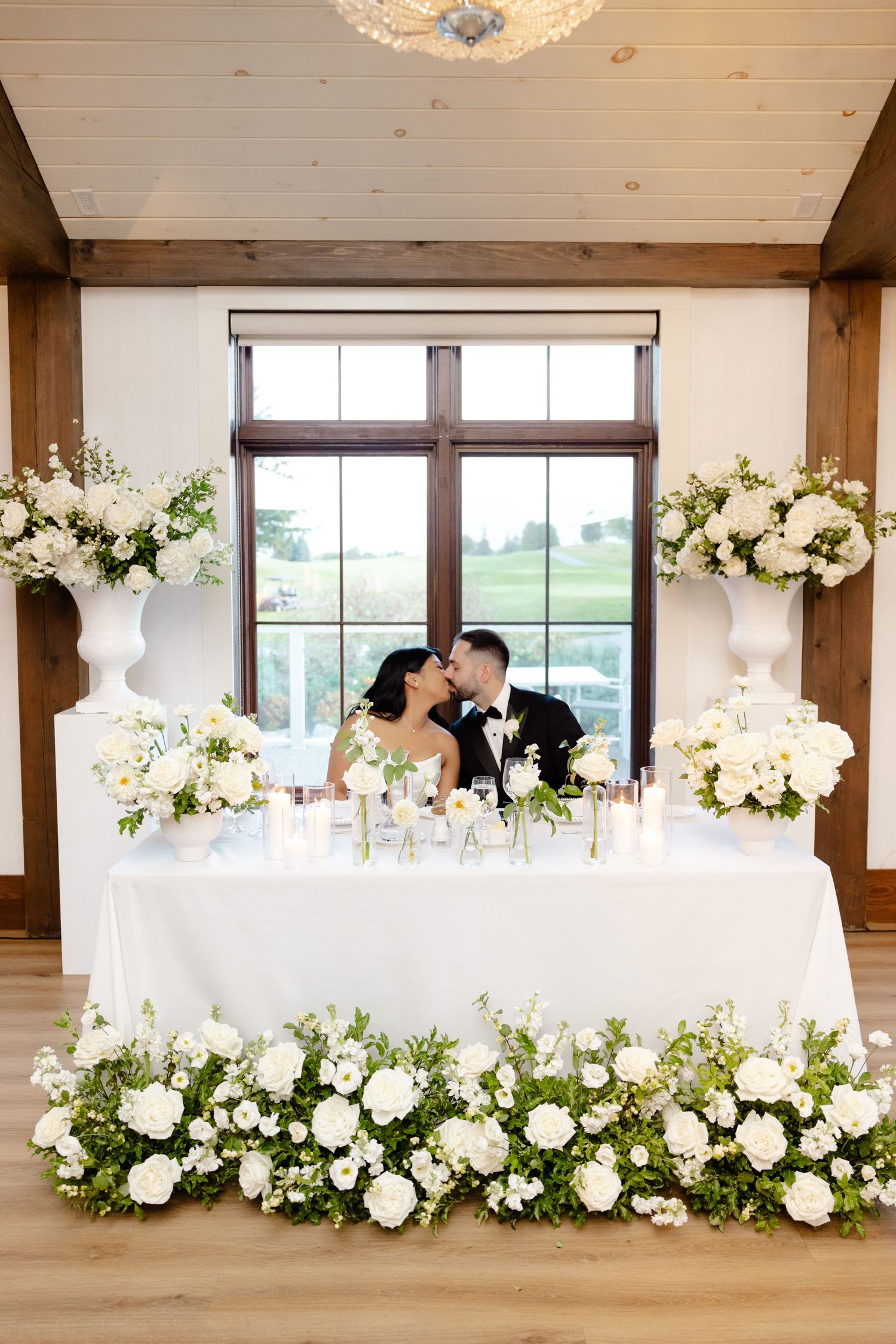 A romantic moment at an elegantly decorated sweetheart table with cascading white flowers.