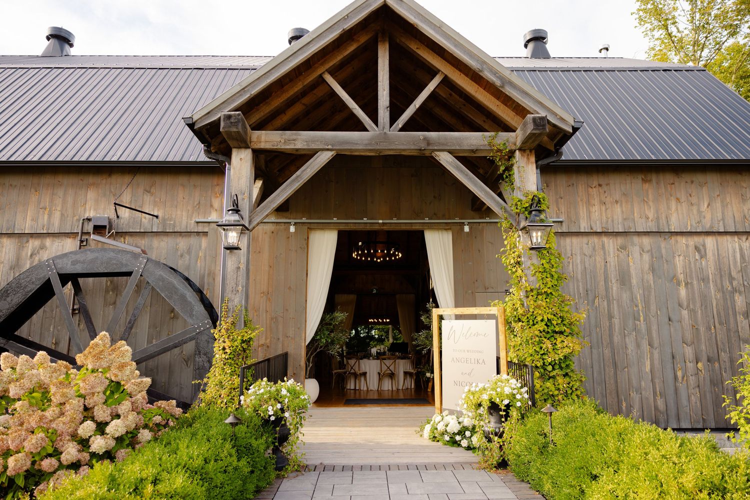 Rustic barn wedding venue entrance with wooden beams and hydrangea flowers.