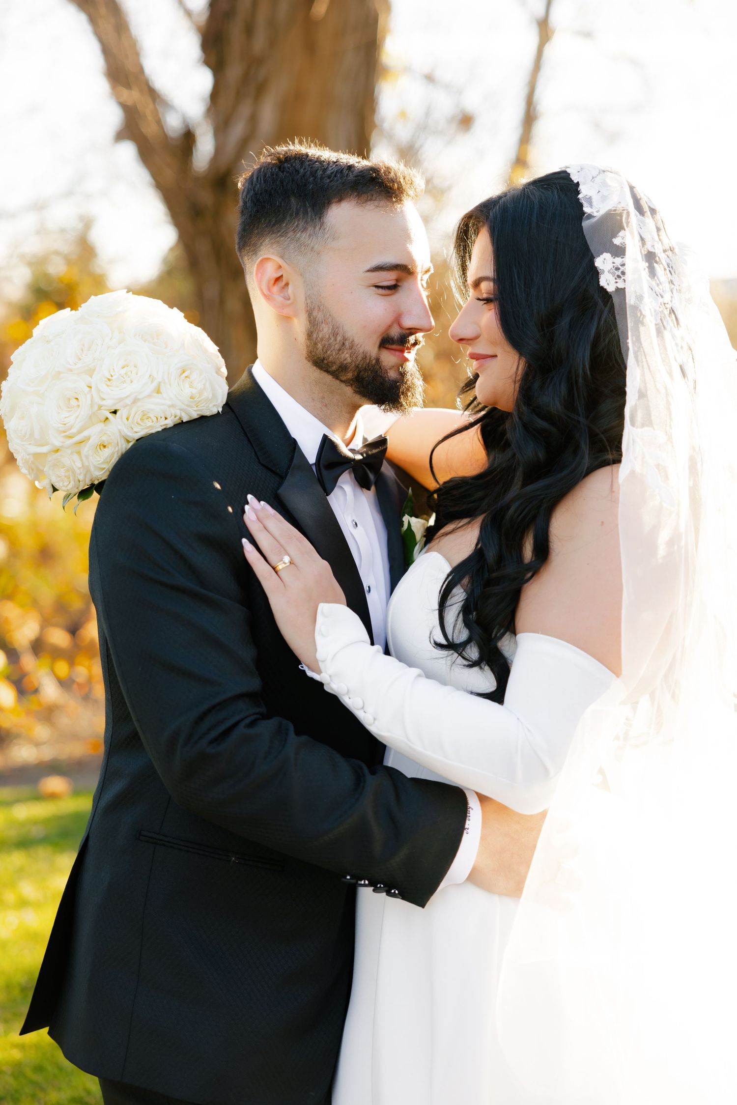 Romantic close-up of newlyweds sharing tender moment in sunlit garden setting.