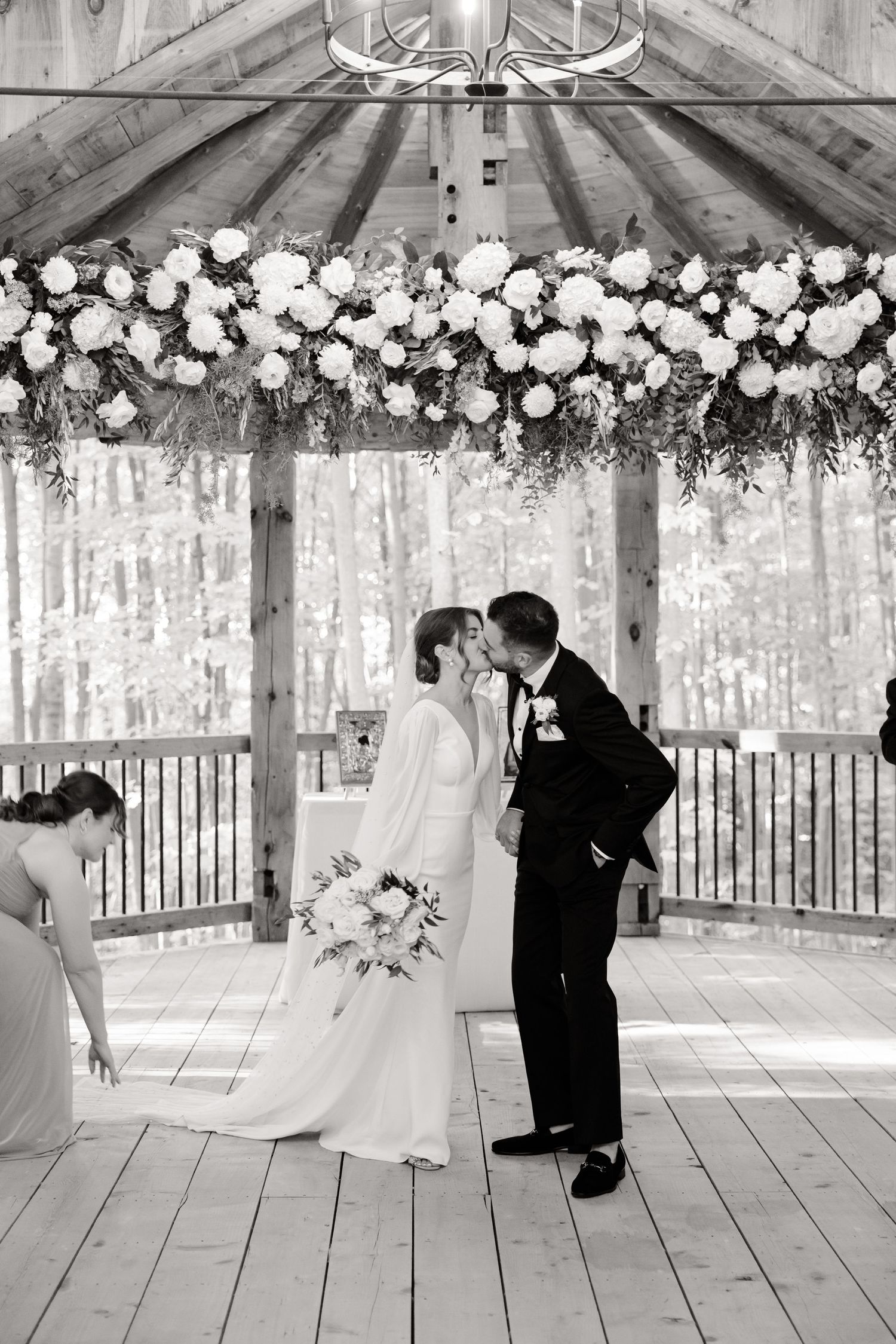 Black and white photo of a wedding ceremony in a garden pavilion decorated with white roses.
