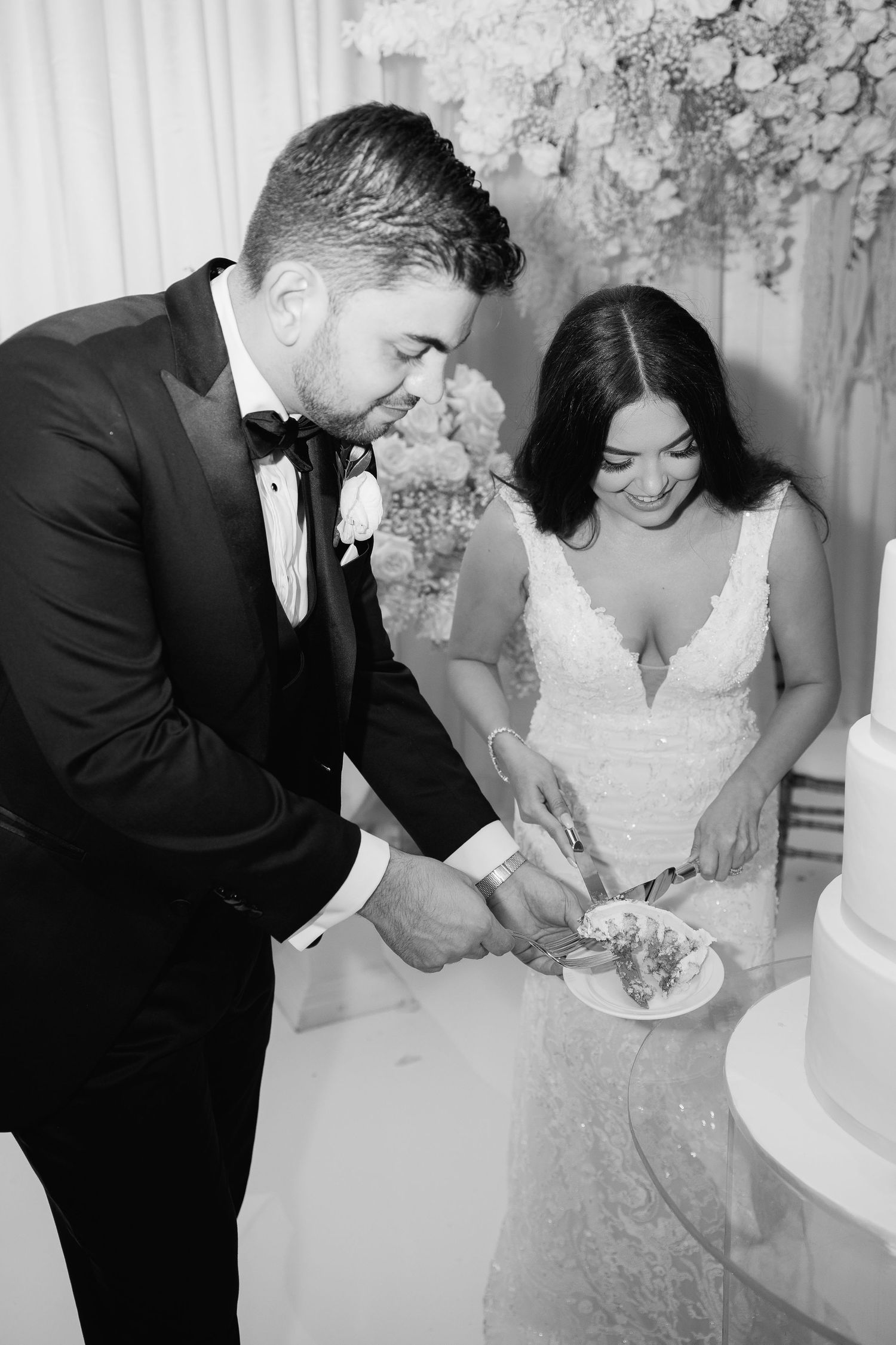 Black and white capture of newlyweds sharing their first slice of wedding cake.