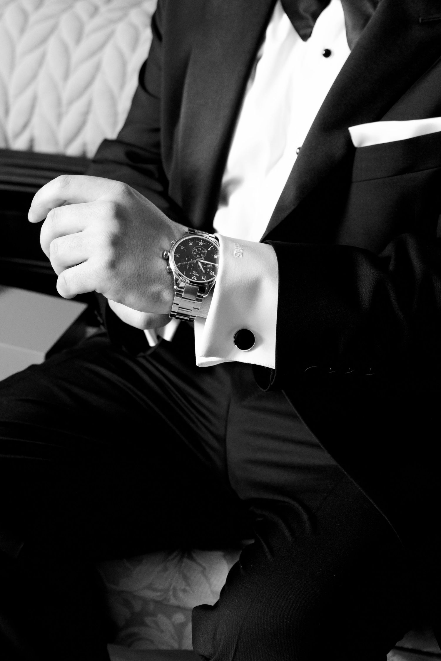 Close-up of man in tuxedo adjusting his luxury watch and cufflink.