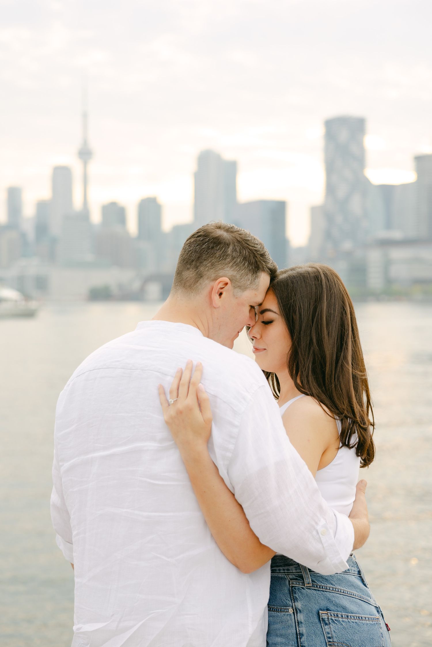 An intimate portrait of a couple in white and denim against the Toronto waterfront.