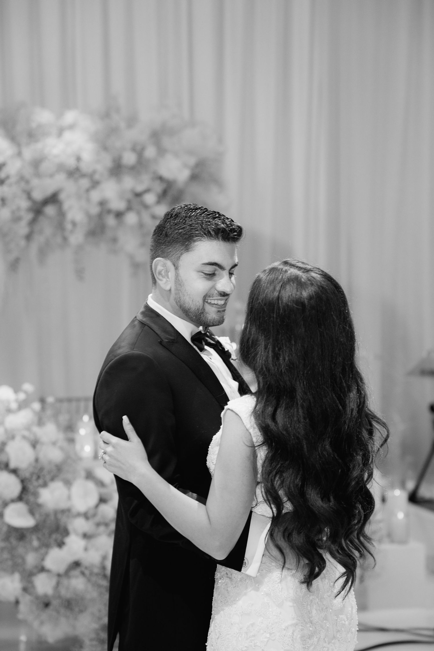 An intimate black and white portrait of a couple sharing a tender moment during their wedding celebration.