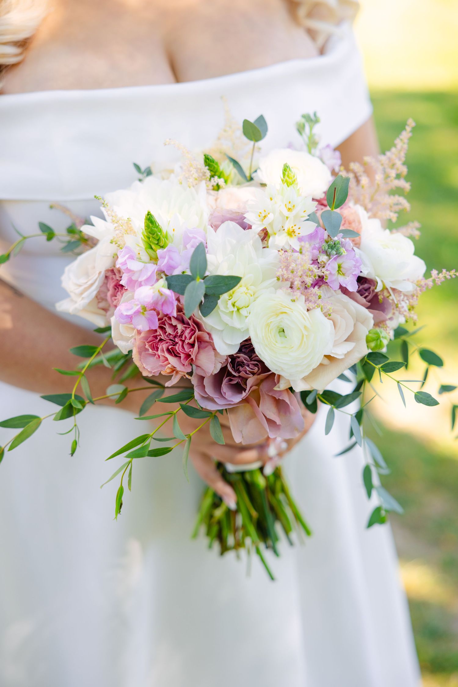 Close-up of romantic bridal bouquet with pink and white flowers and delicate greenery.