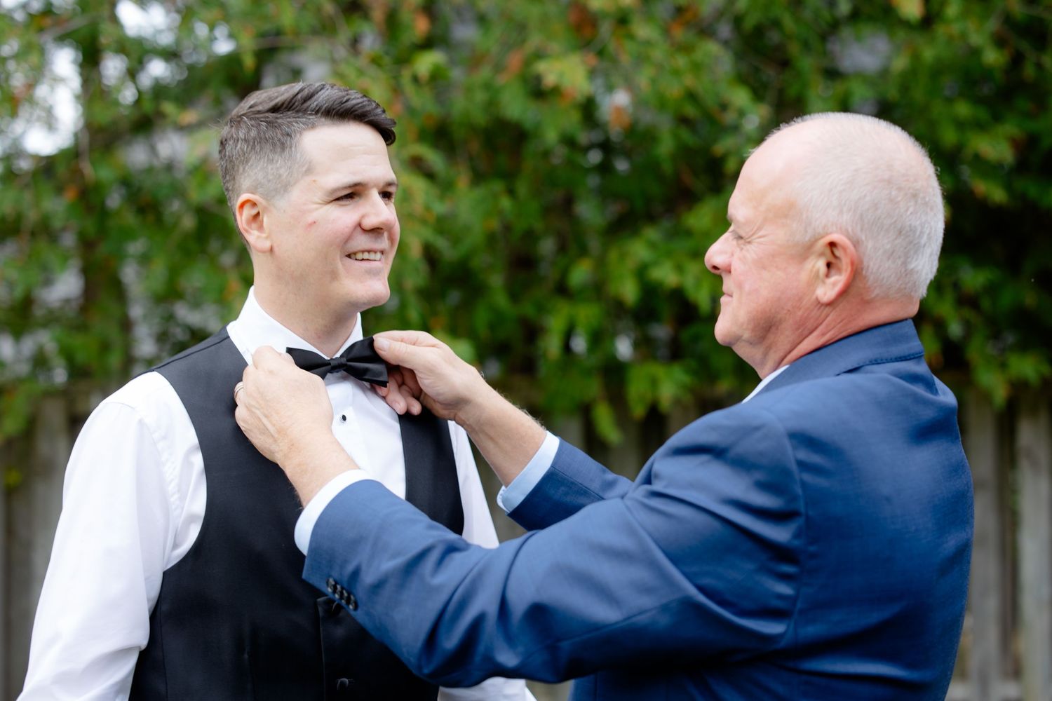 A heartwarming moment as someone helps adjust a bow tie before the wedding ceremony.