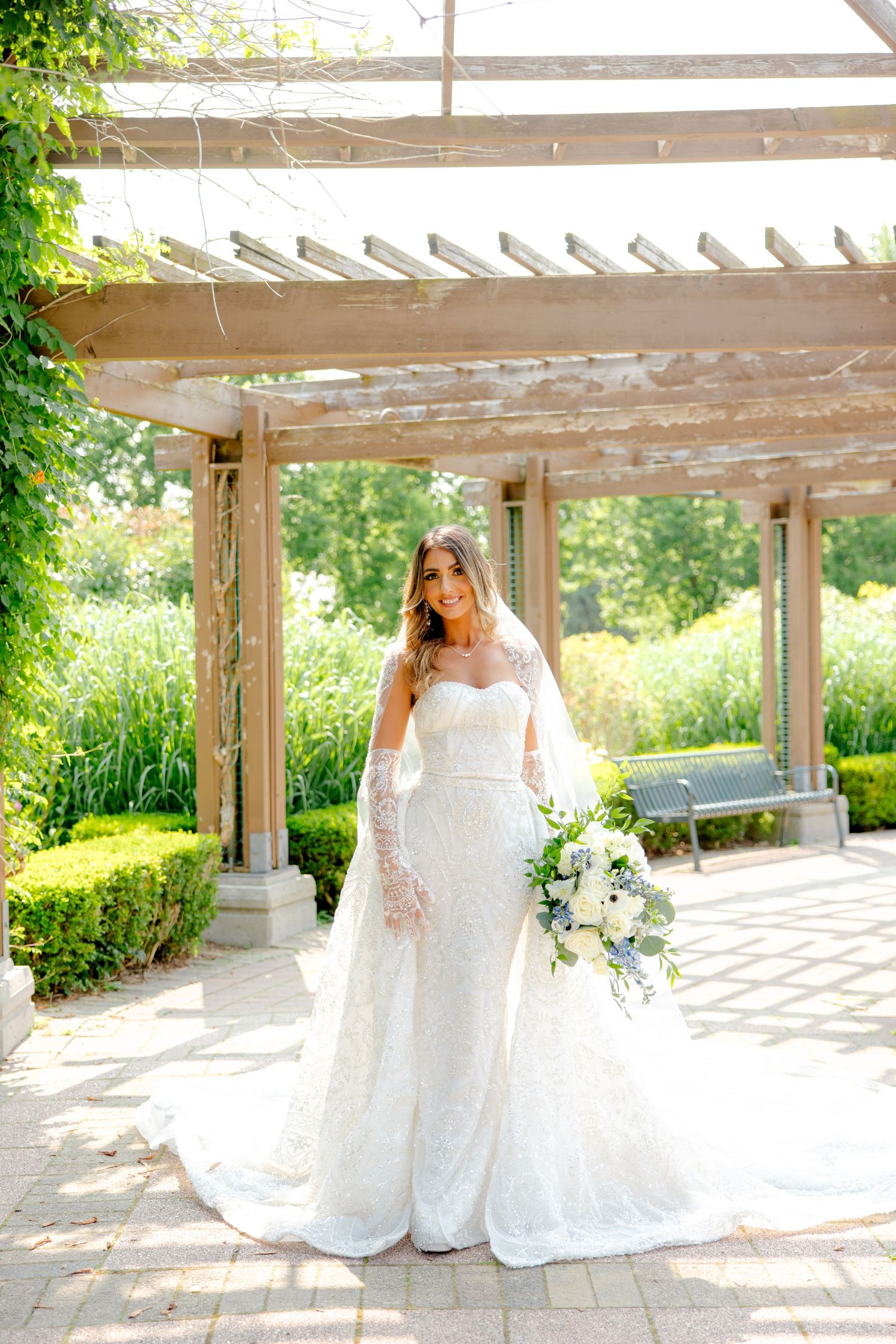 Classic bridal portrait featuring sweetheart neckline gown and cathedral veil in garden setting.