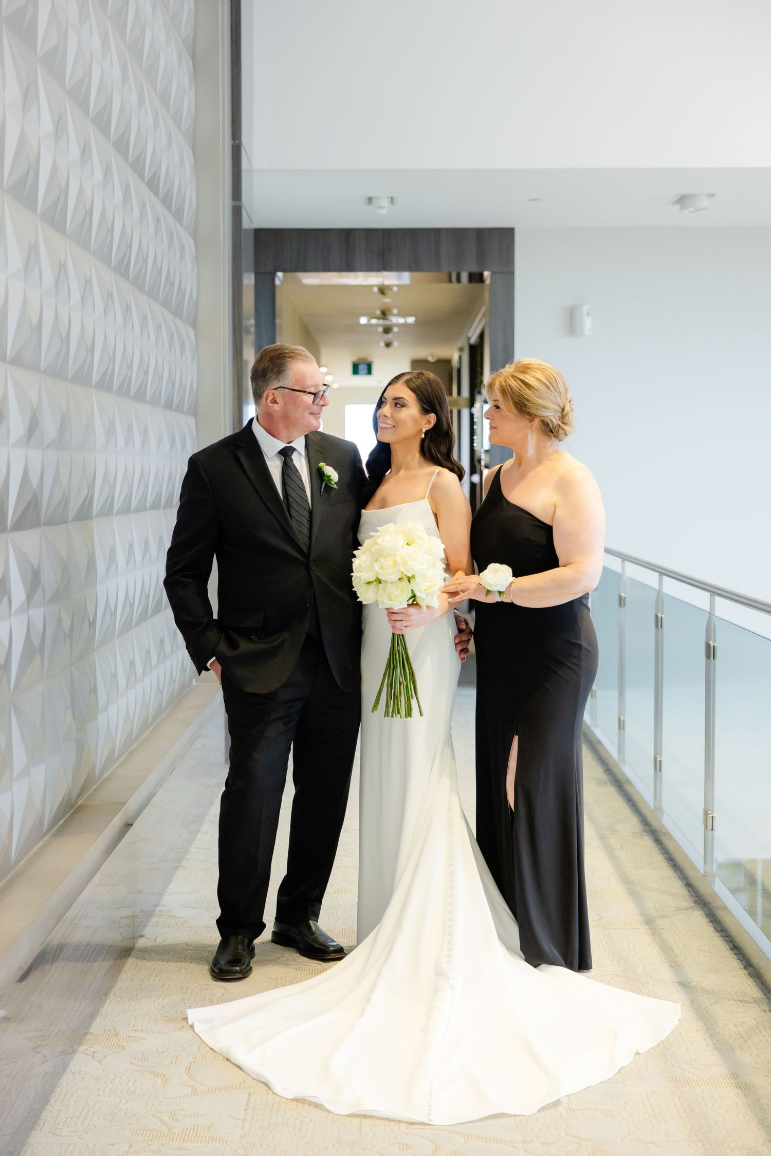 Formal wedding portrait in modern hallway with dramatic white textured wall.