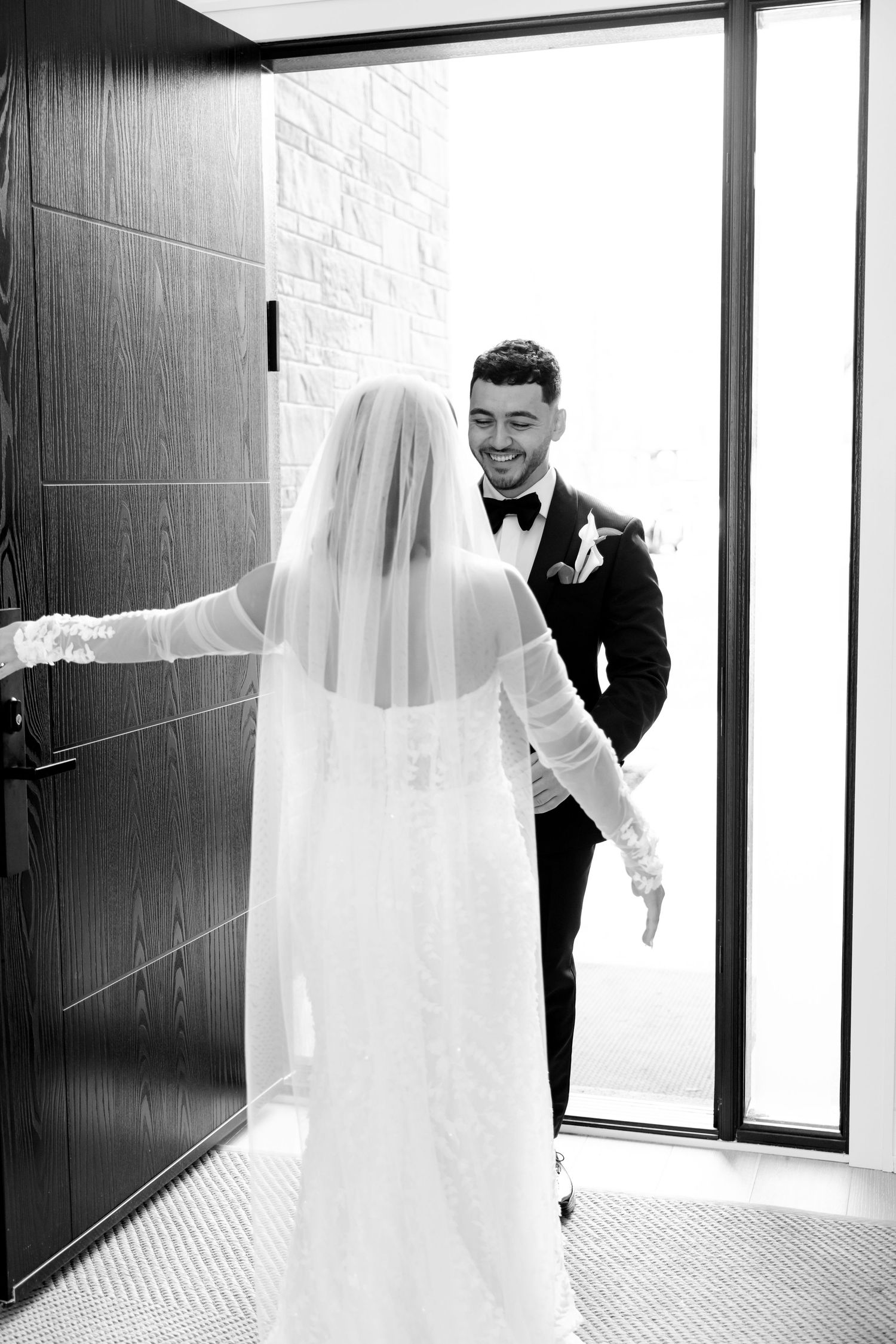 A joyful first look wedding moment captured in black and white photography.