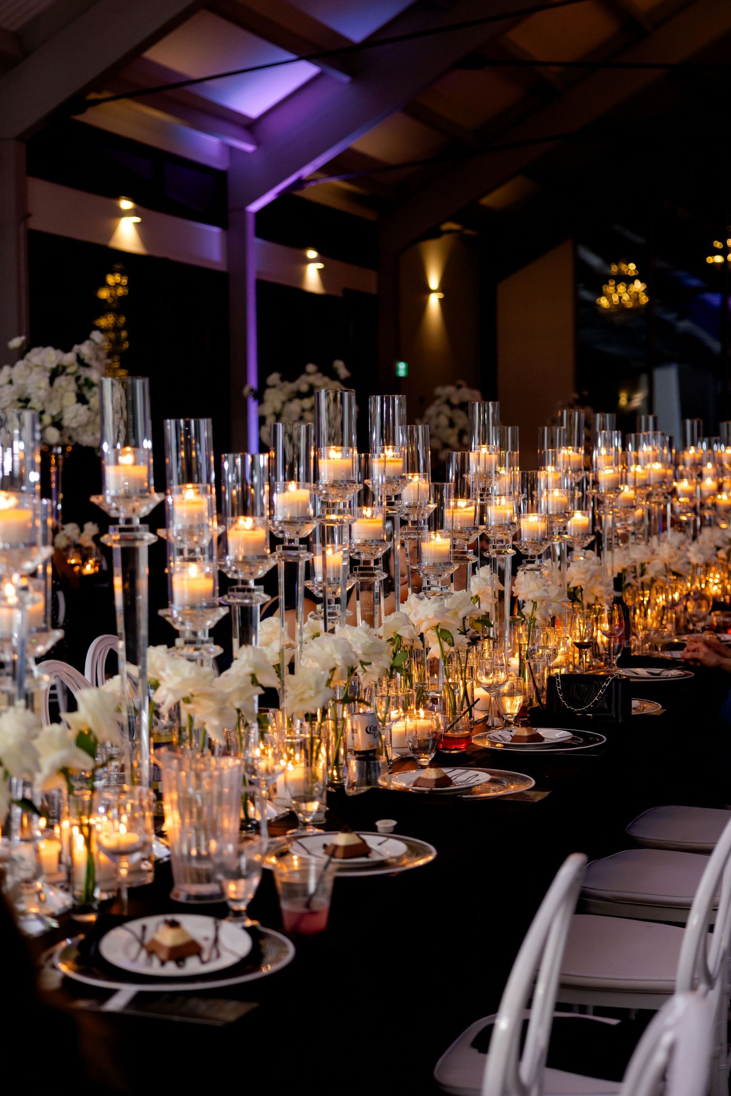 Elegant tablescape with crystal candleholders, white orchids, and gold accents at wedding reception.