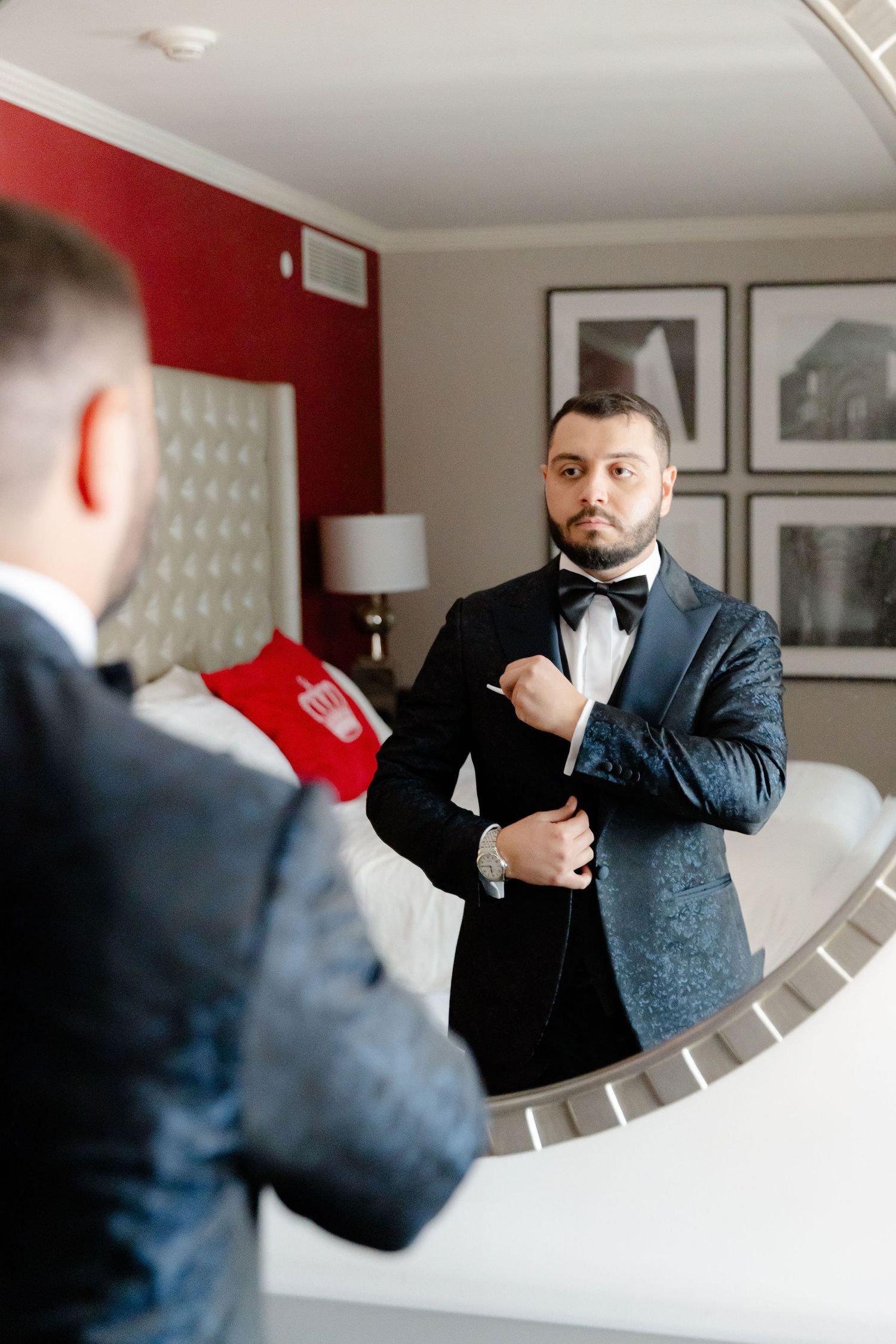 A sequence of formal attire adjustments reflected in an elegant mirror against a red and white wall.