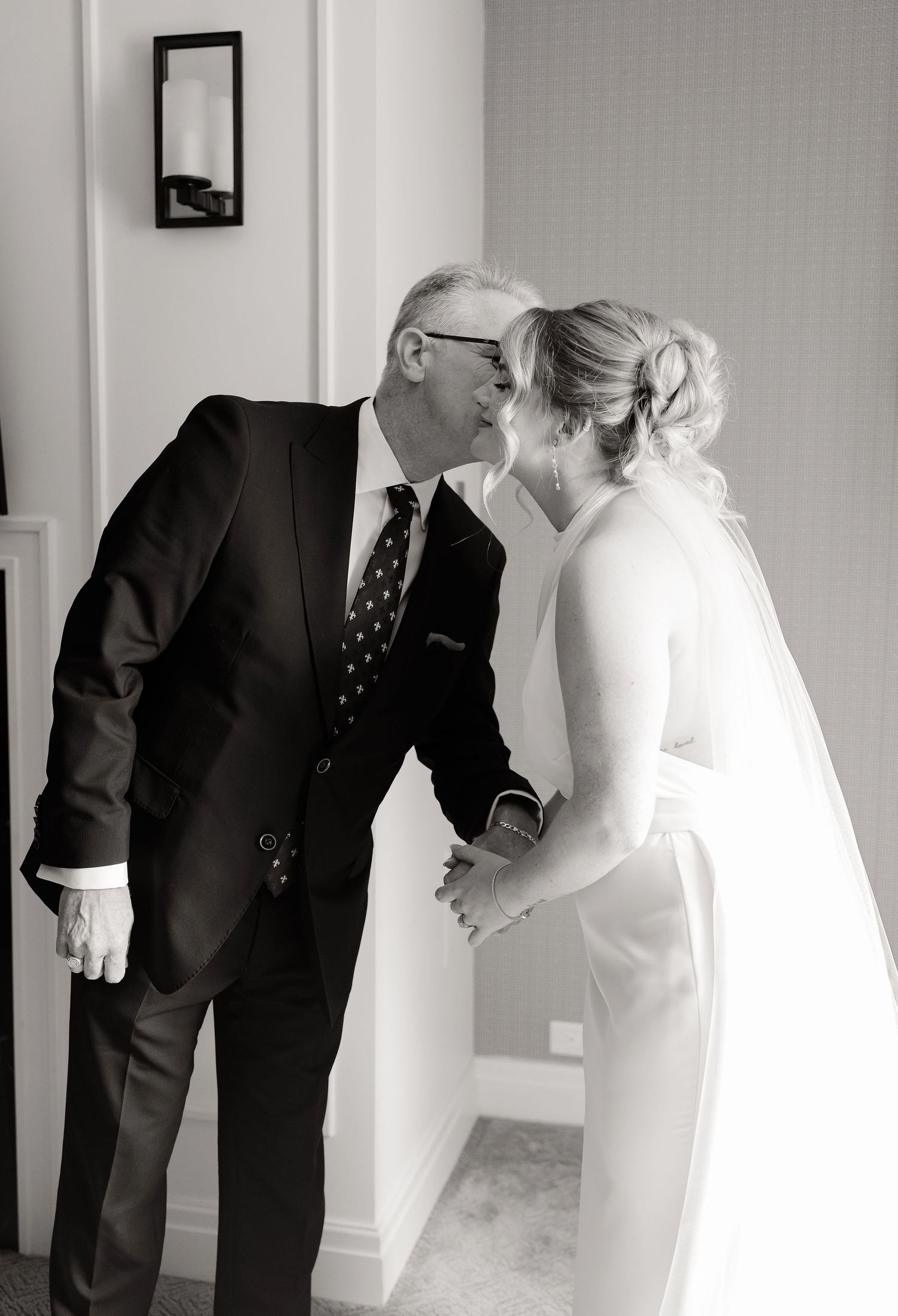 Black and white candid moment between a bride in white and a man in a dark suit.