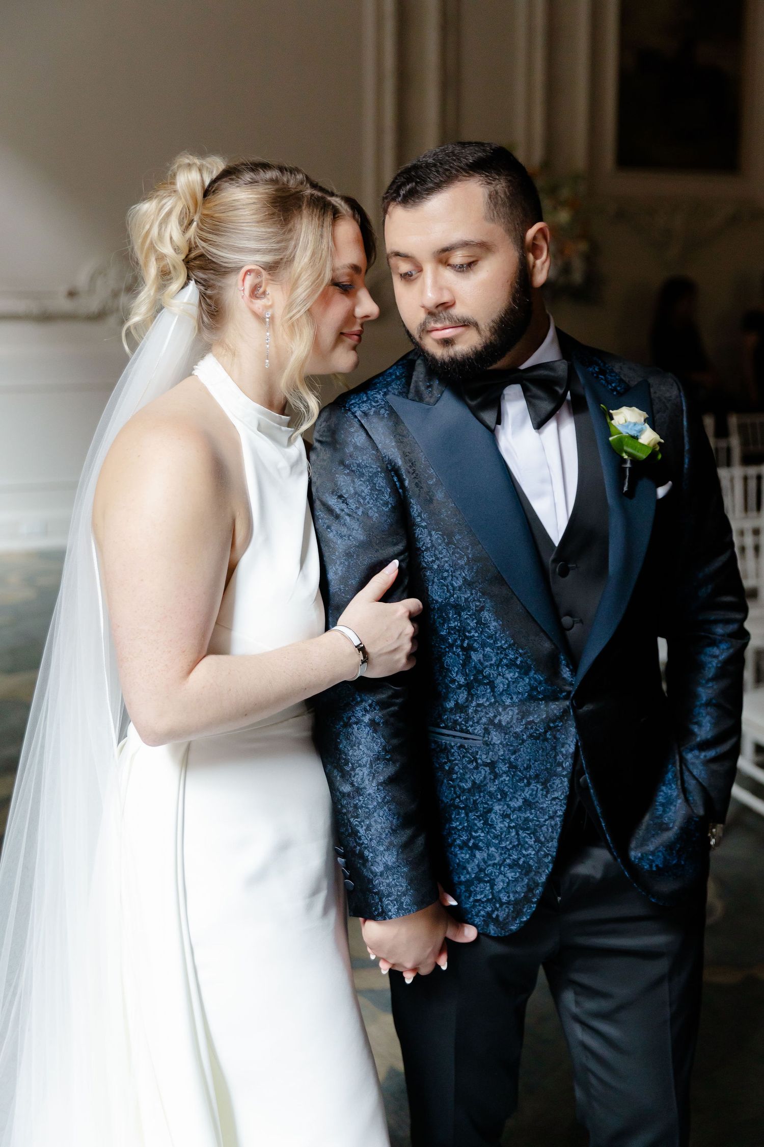 Romantic wedding couple in formal attire sharing intimate moments against dark background.