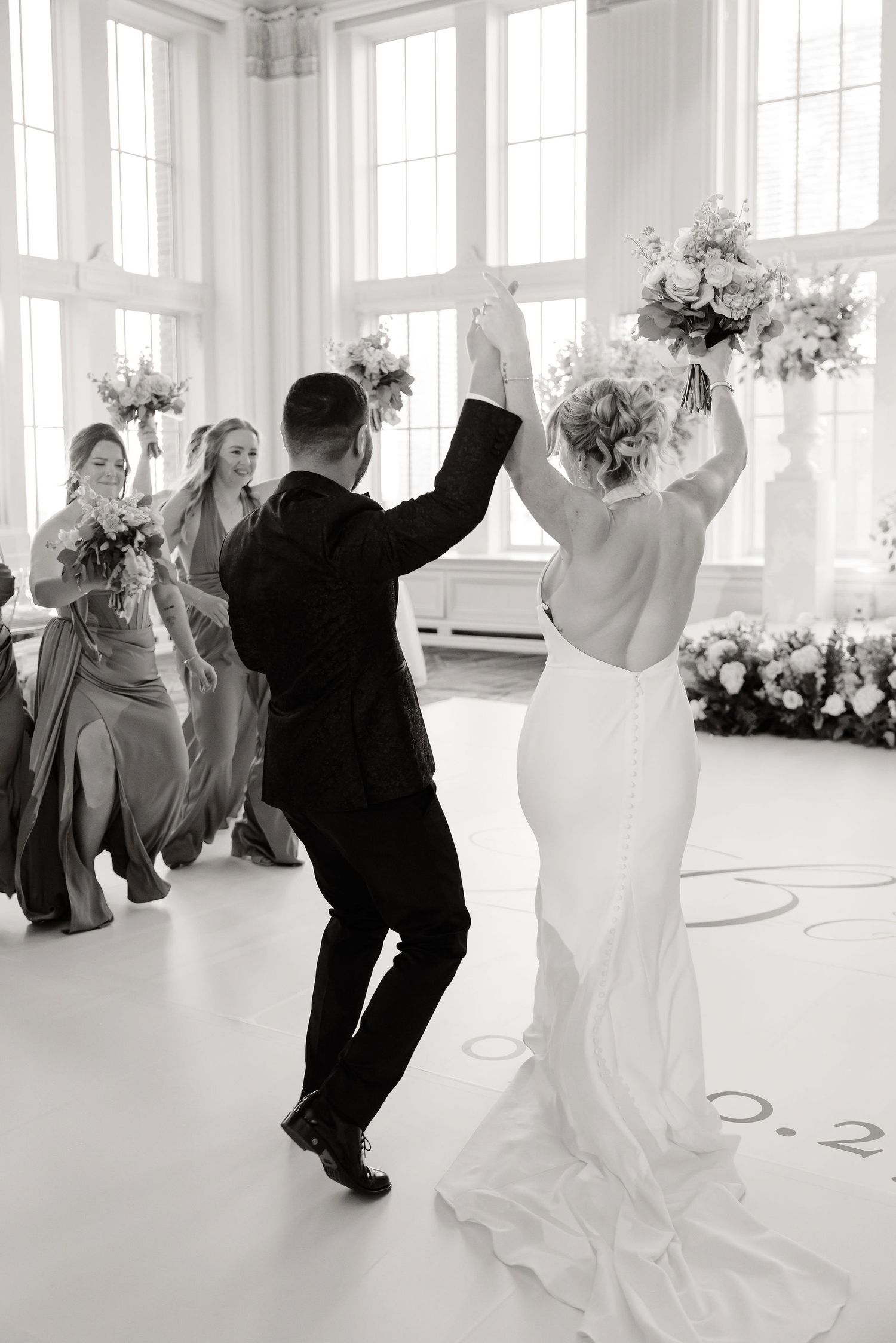 Black and white photo sequence shows a couple dancing in an elegant white ballroom with graceful movements.