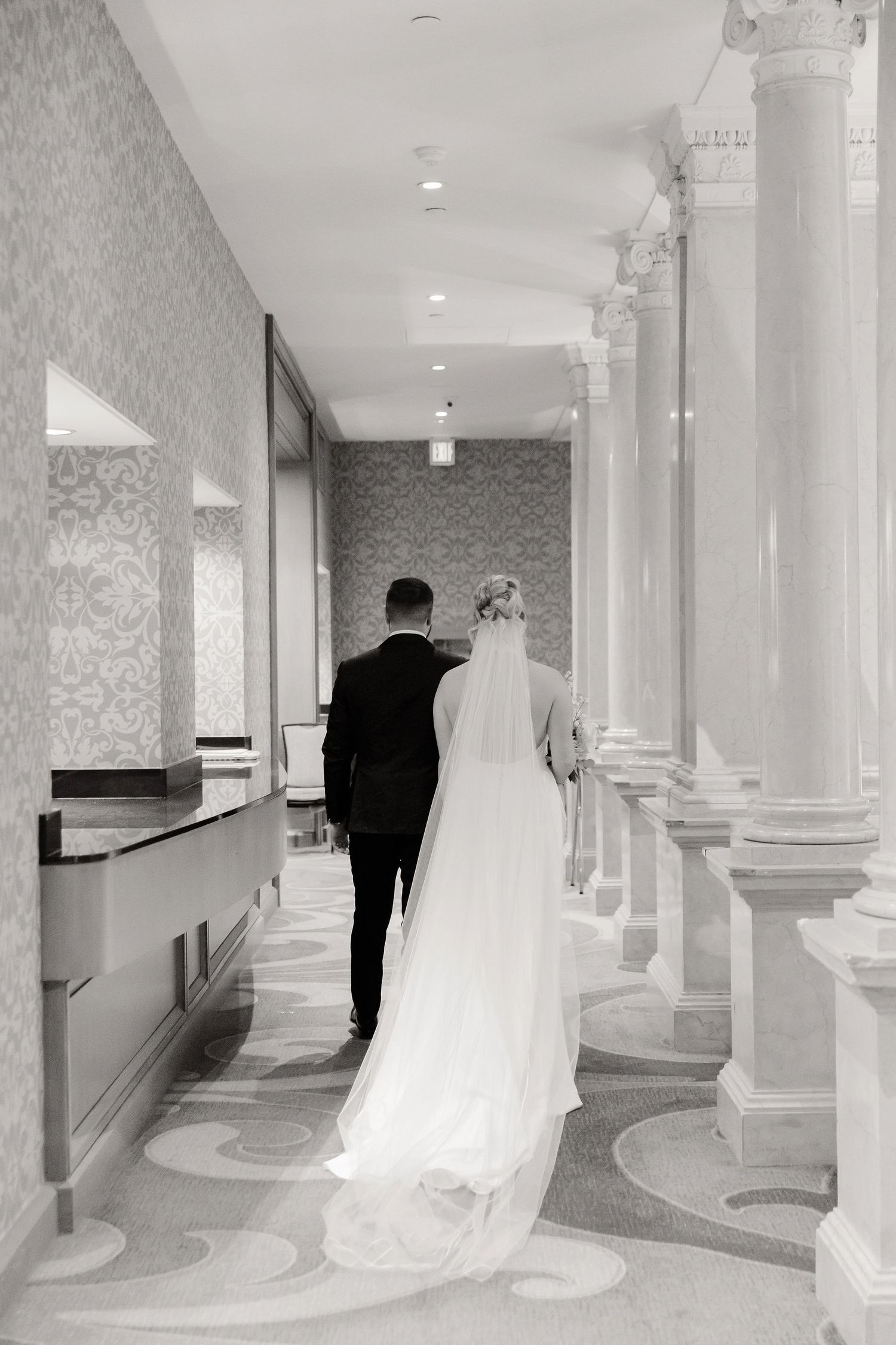 A sequence of black and white photos showing a wedding dress train flowing down an elegant hallway with ornate columns.