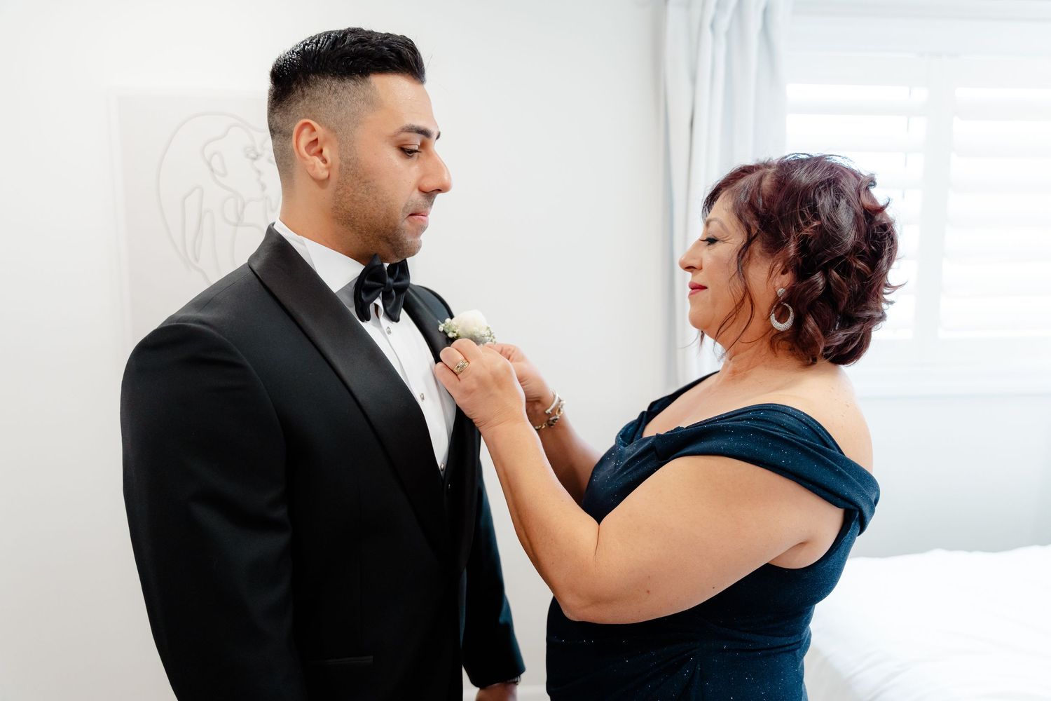 A heartfelt interaction between two people during formal wedding preparations.