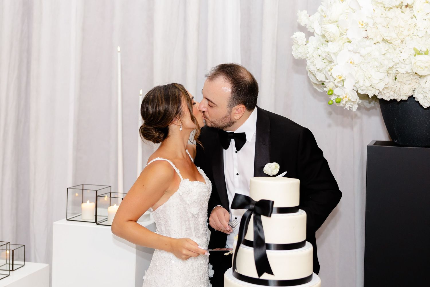A bride and groom share a sweet moment while cutting their elegant black and white wedding cake.