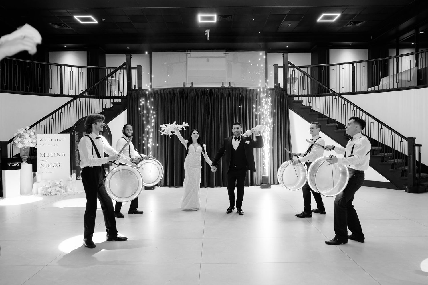 Black and white photo of traditional wedding drummers performing in symmetrical formation.