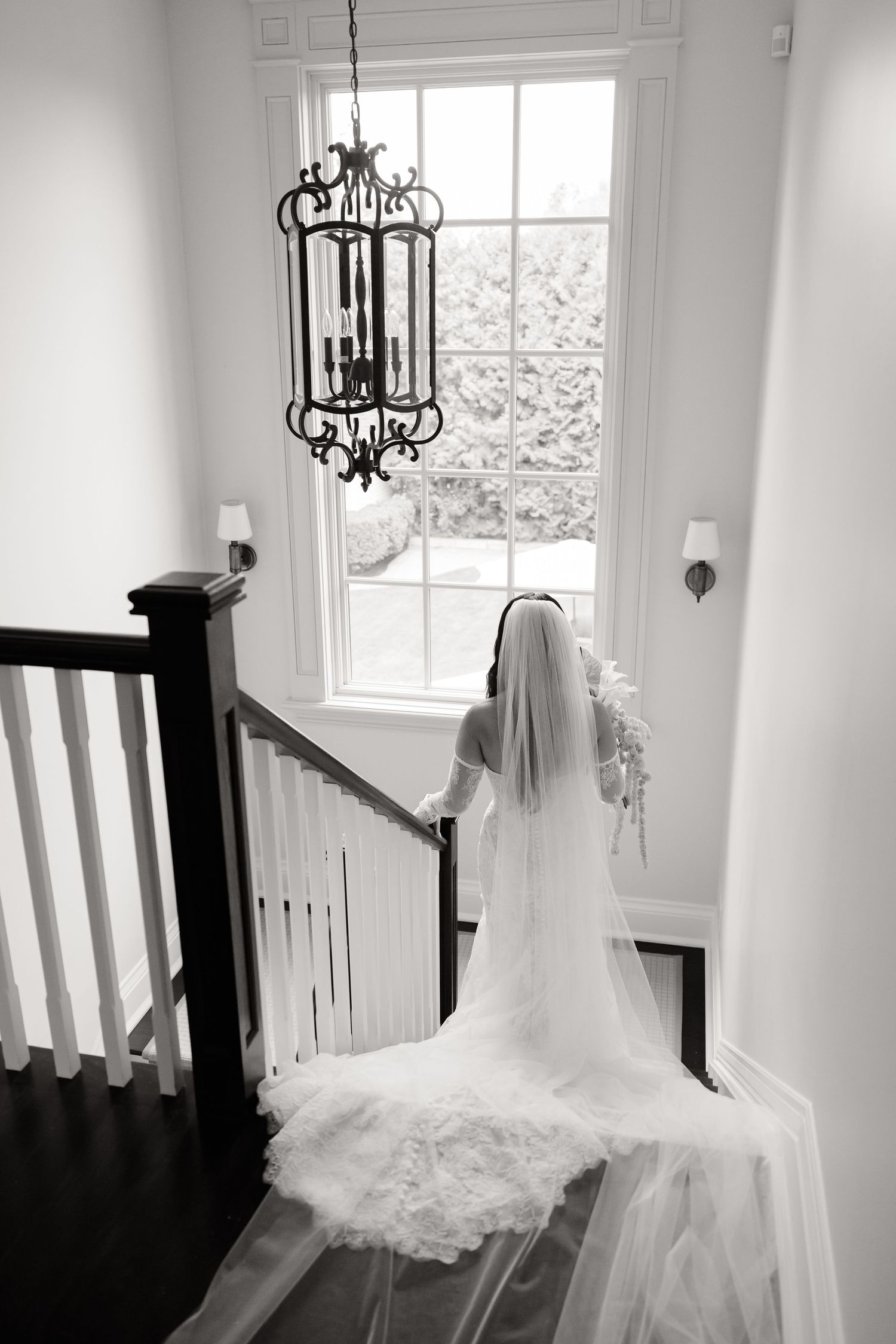 Elegant bridal gowns photographed in a bright interior setting with natural window light and chandeliers.