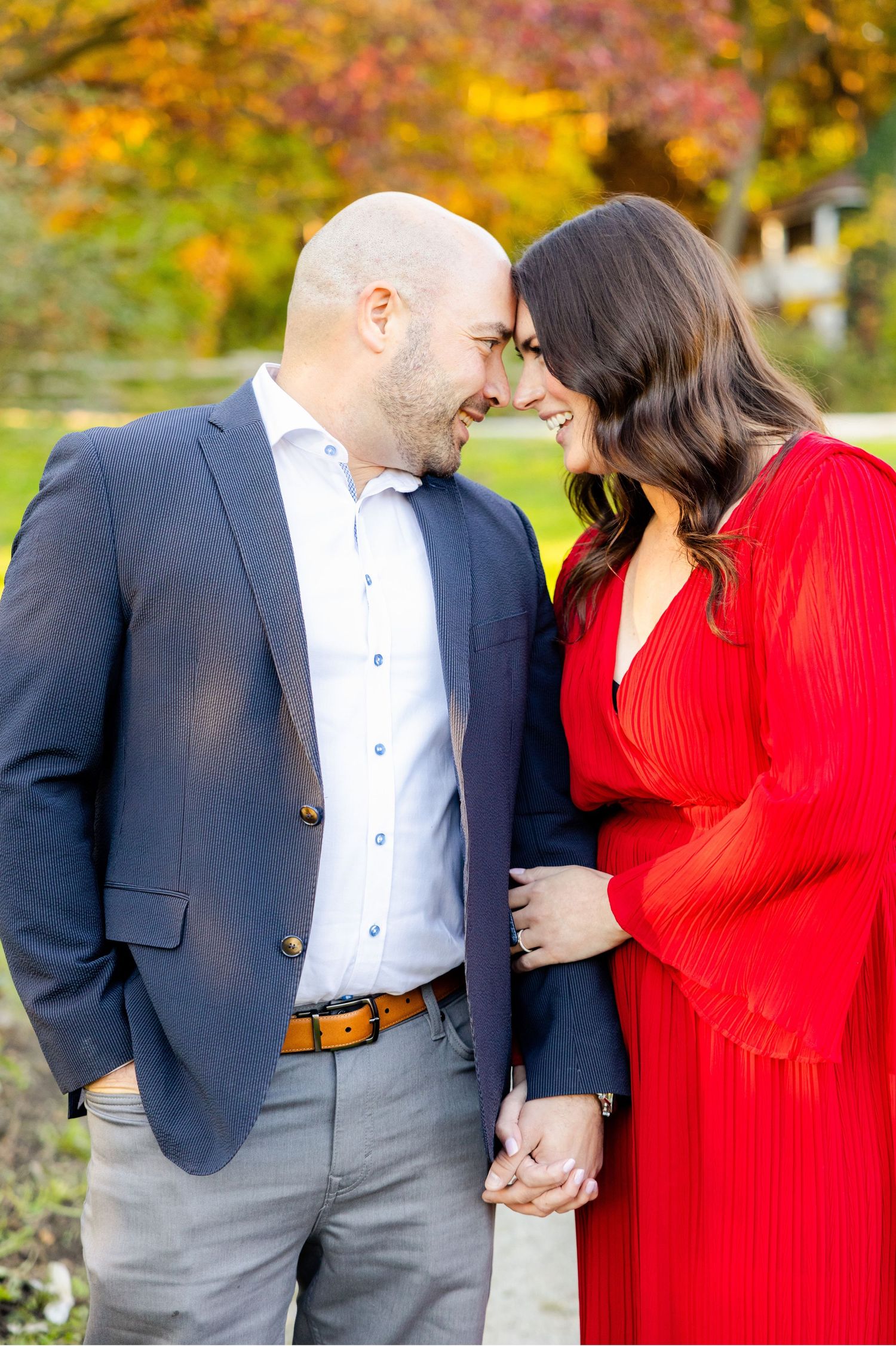 A couple shares an intimate moment surrounded by gorgeous autumn colors in a garden setting.