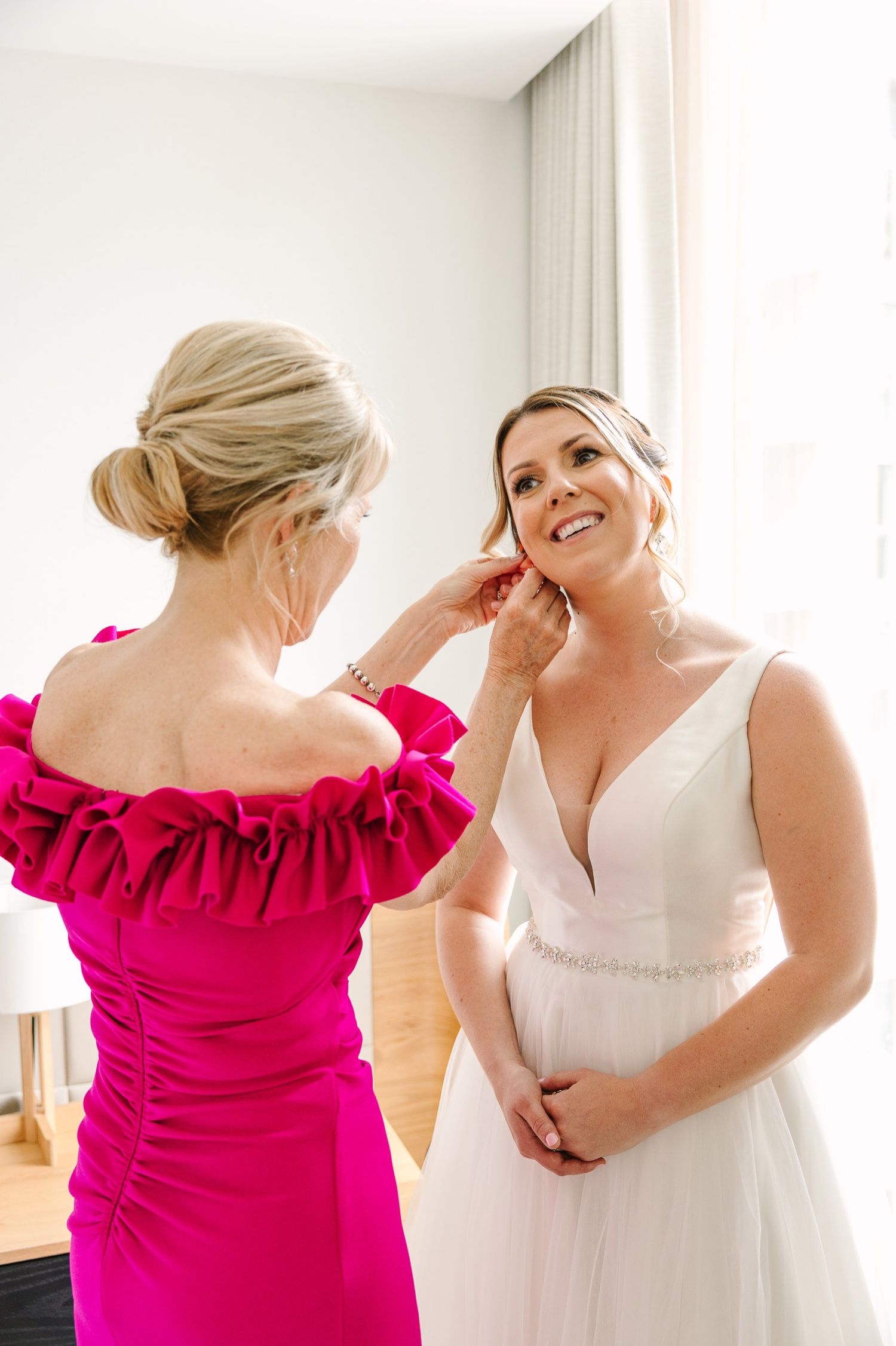 Final touches being made to wedding attire with bright pink accent dress.
