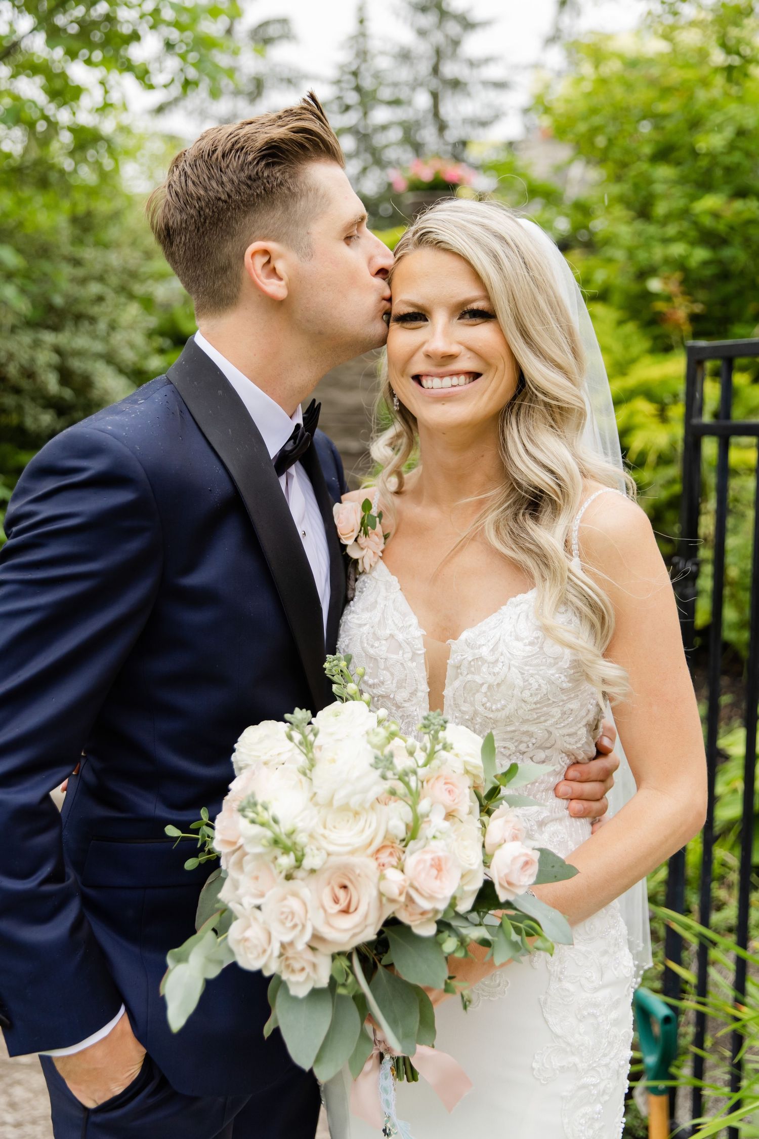 Romantic moment between newlyweds with bride holding blush and white rose bouquet.