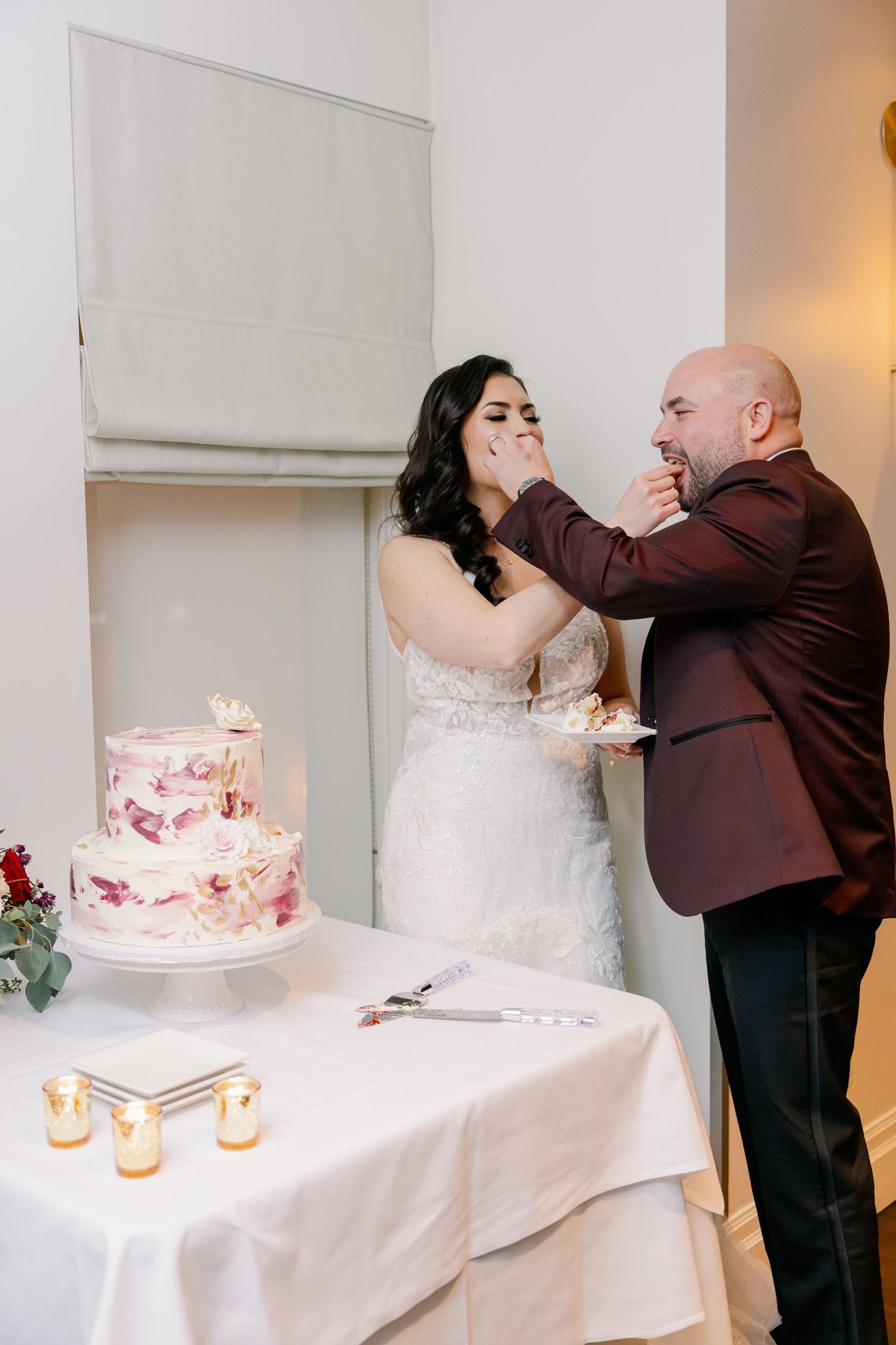 Wedding cake cutting celebration with pink tiered cake and playful cake smash moment.