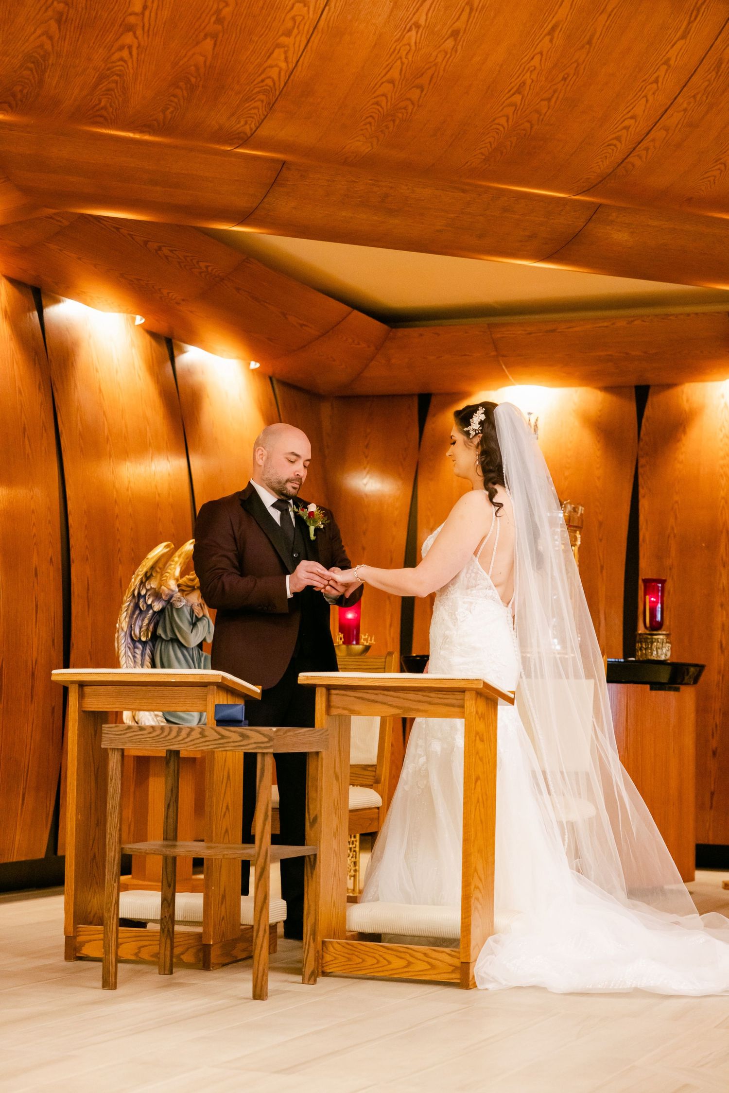 Wedding ceremony exchange in front of wooden paneled walls with warm spotlighting.