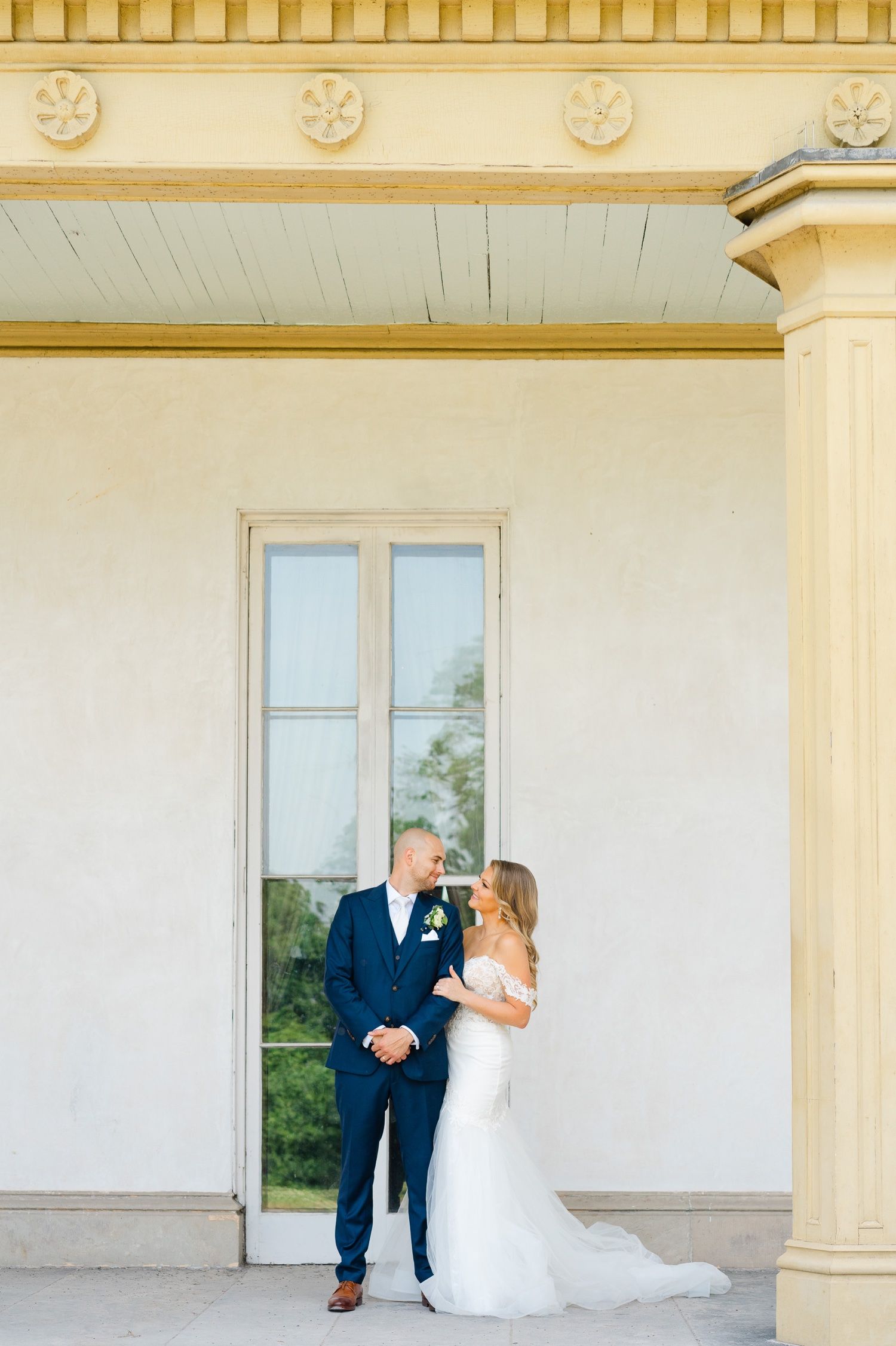 An elegant wedding portrait framed by cream columns and architectural details.