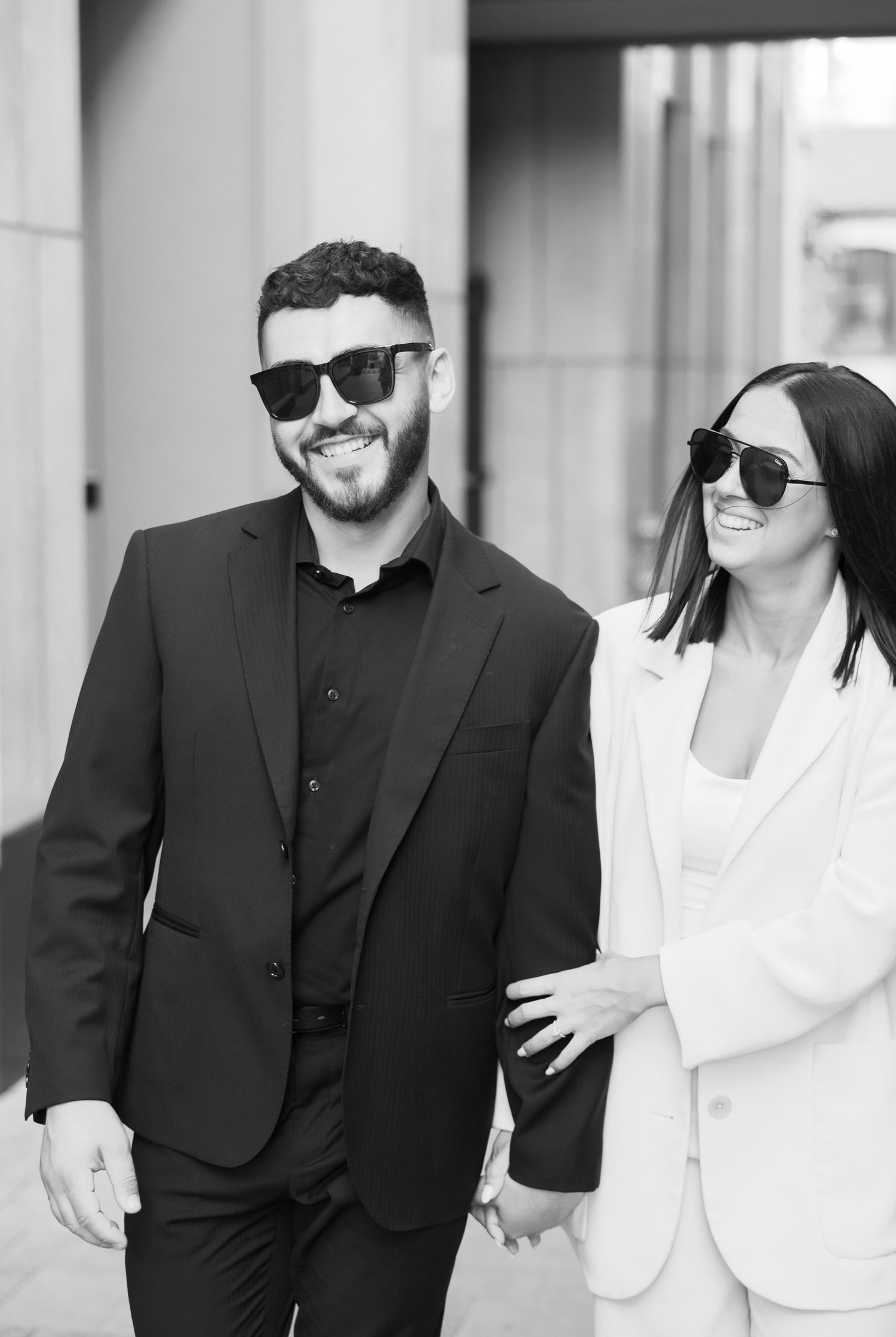 Happy couple in sunglasses and formal attire sharing a candid moment.
