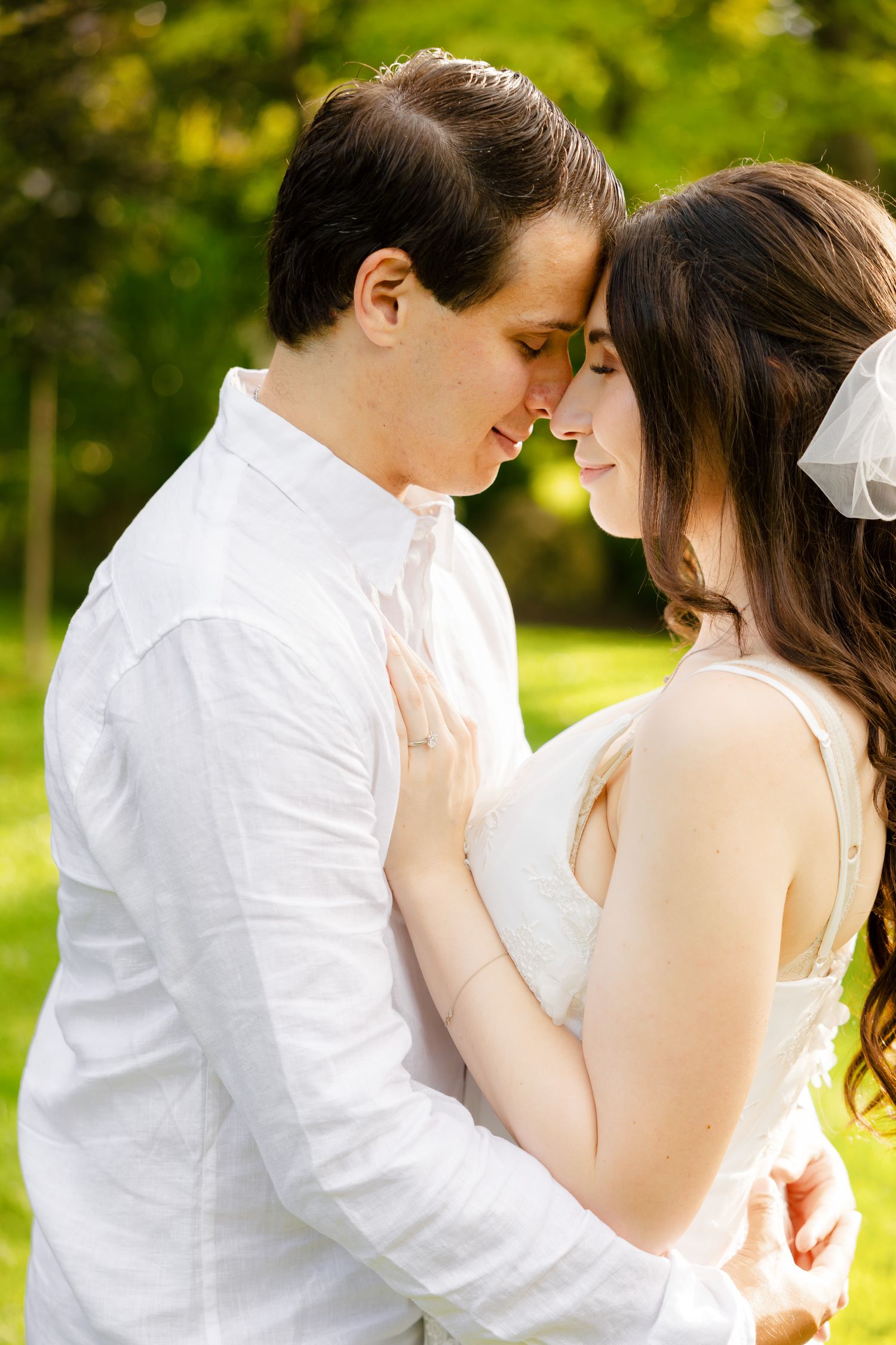 A romantic wedding couple shares a tender moment in a garden setting with soft natural lighting.
