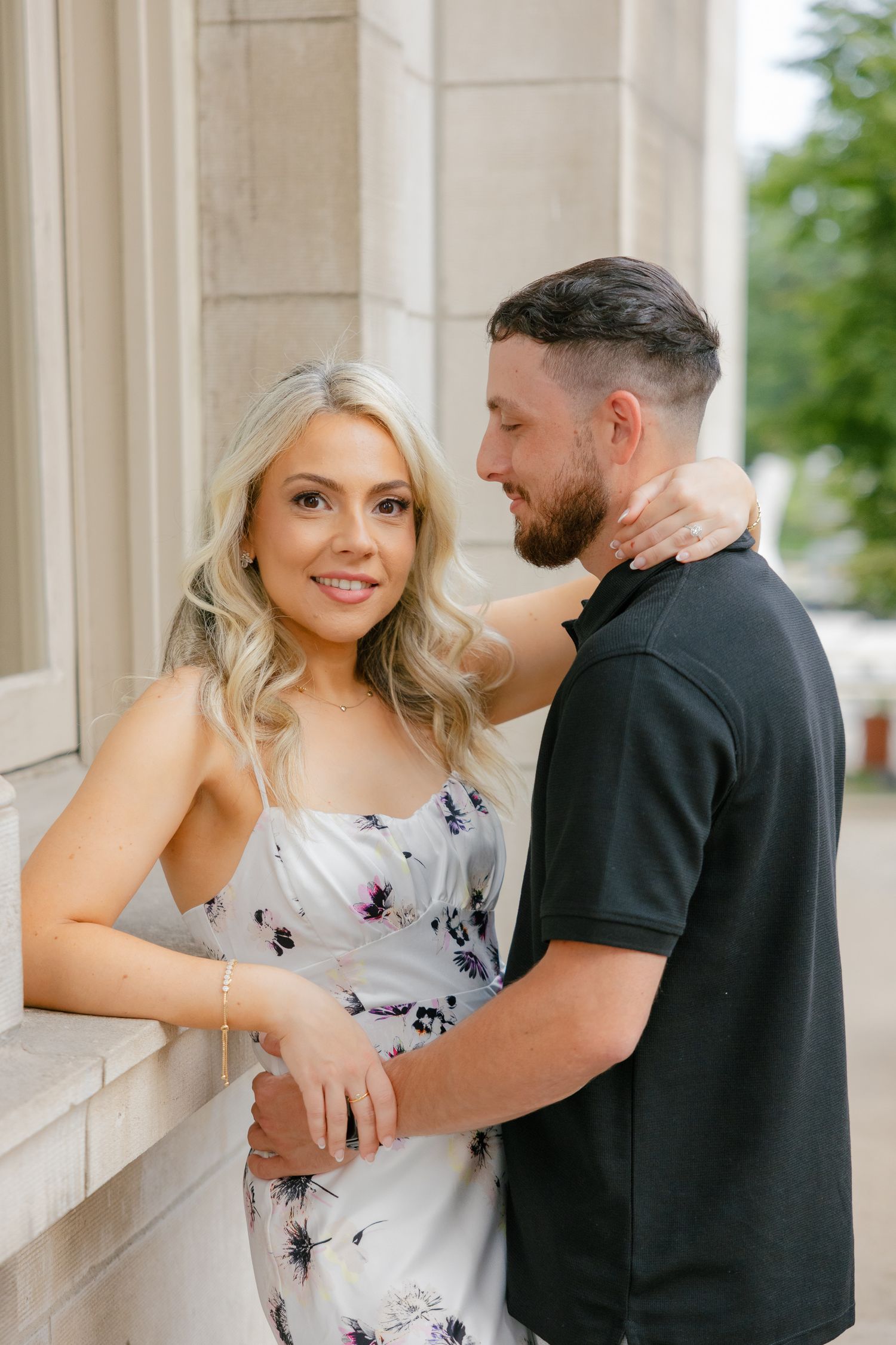 A couple poses playfully against a stone column backdrop.