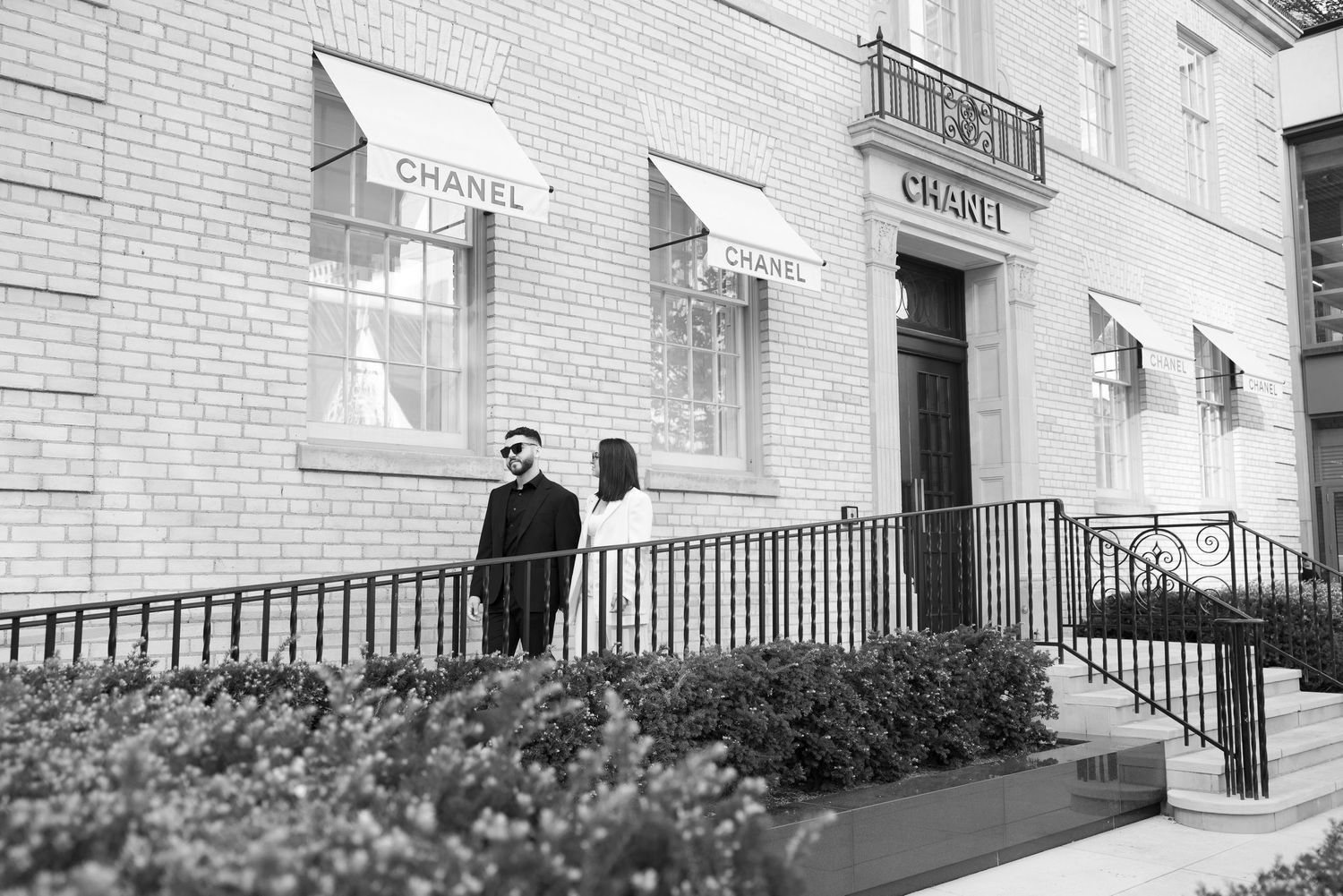 Black and white photo of a Chanel store exterior with white brick facade and awnings.