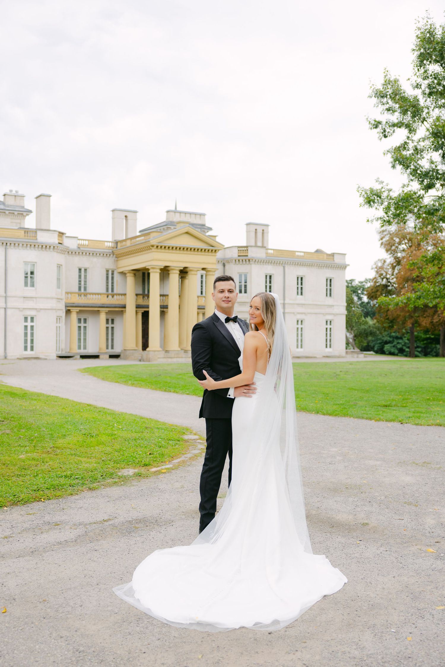 Wedding portrait with stunning neoclassical mansion backdrop and flowing white dress.