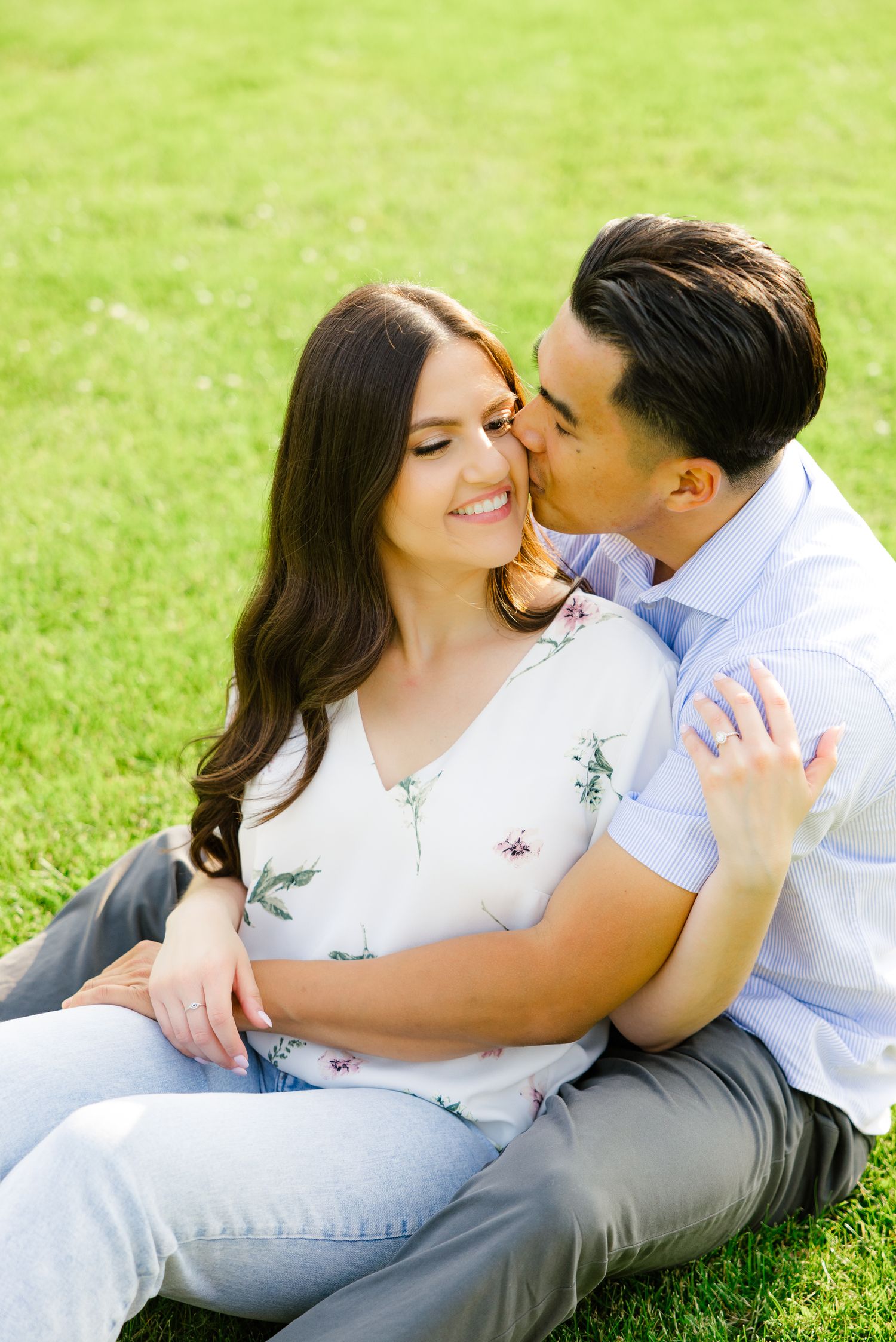 An intimate moment between a couple sitting together on bright green grass during summer.