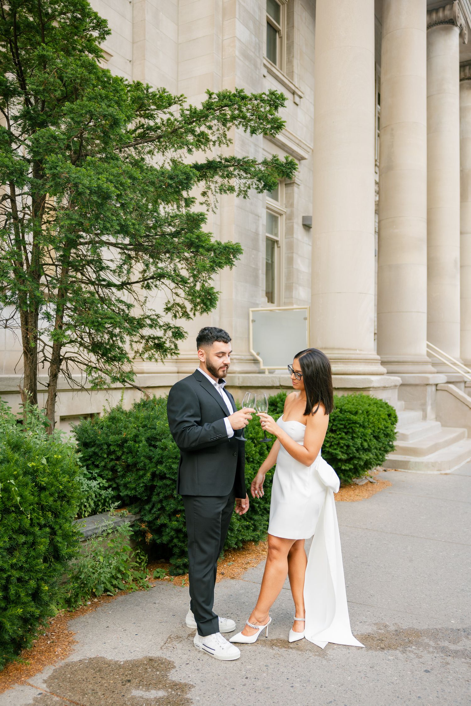Couple in formal wear engaging in conversation by ornate building columns.