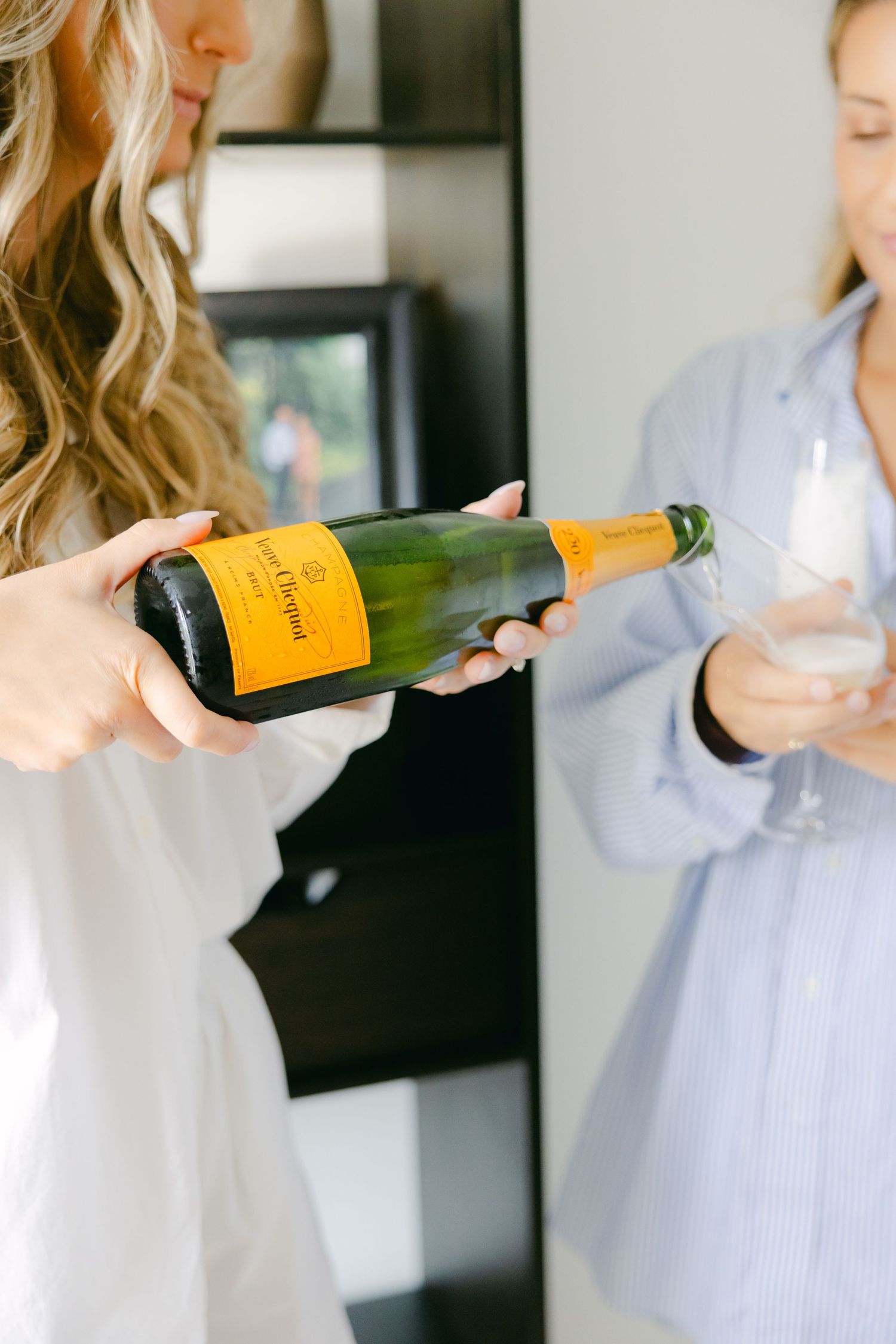 Pouring champagne between two people during wedding day preparations.