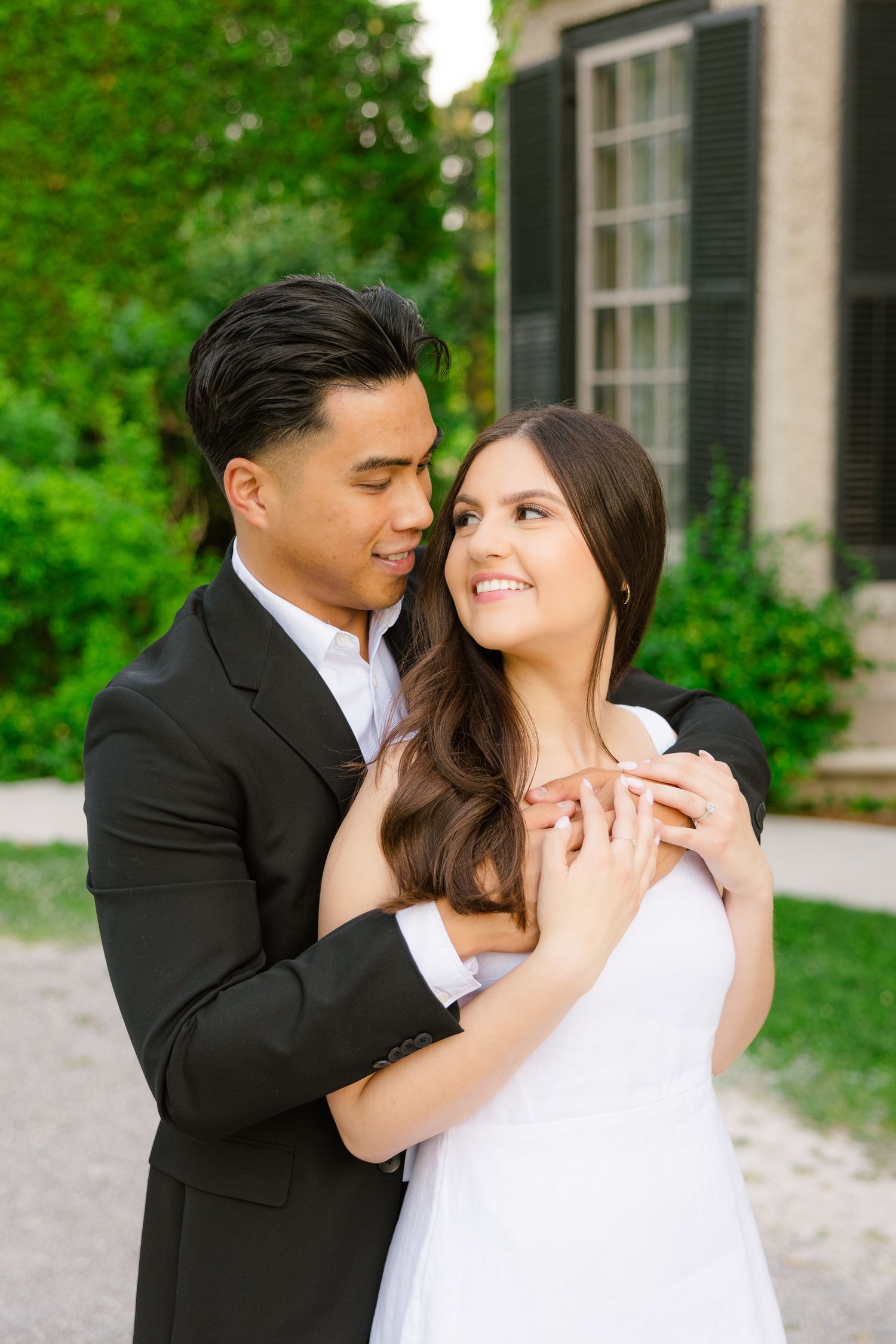 Romantic couple in formal wear share intimate moment in garden setting.